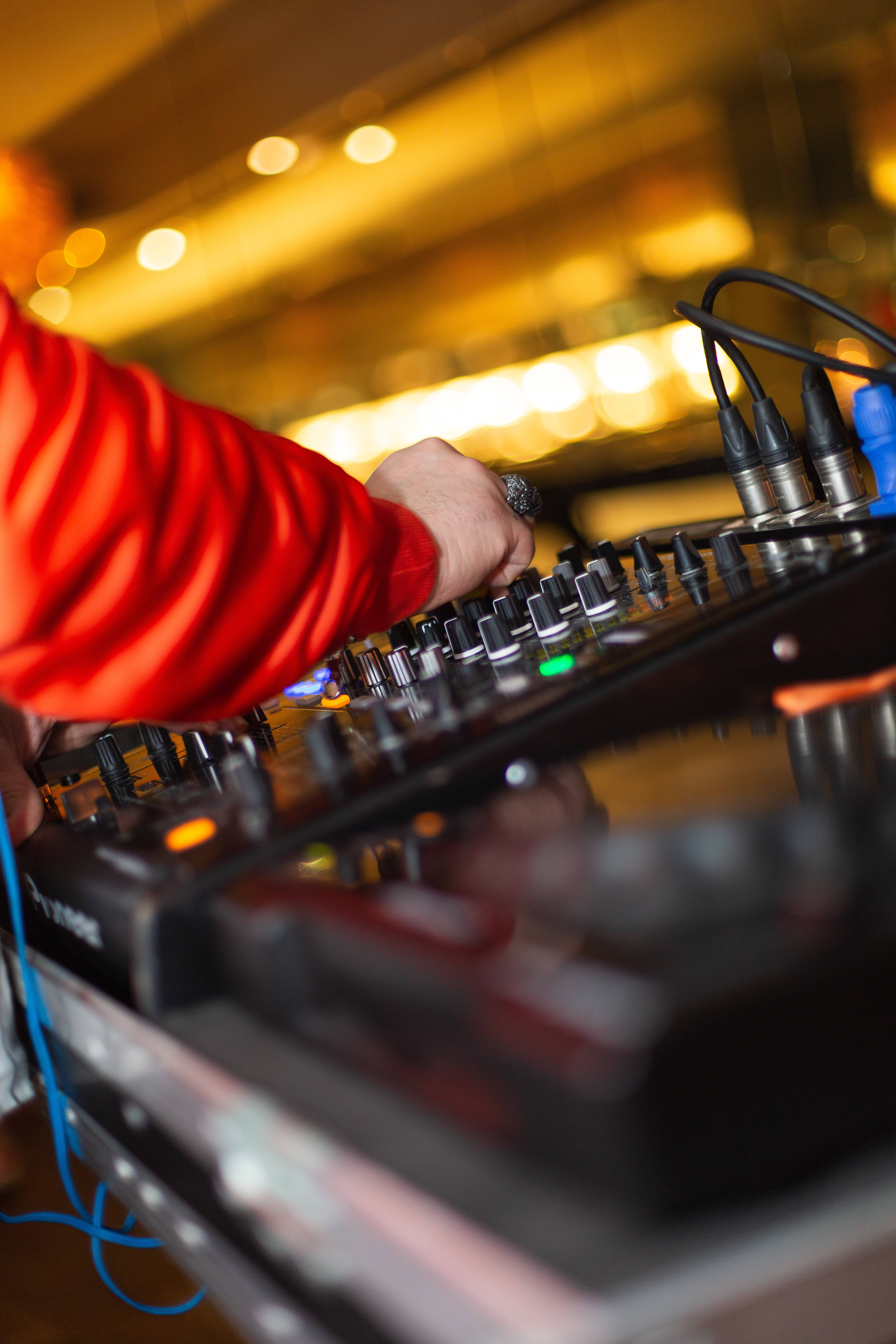 DJ 桌布 壁紙 — DJ的手在溫暖的金色燈光下調整黑色混音器上的旋鈕的特寫。