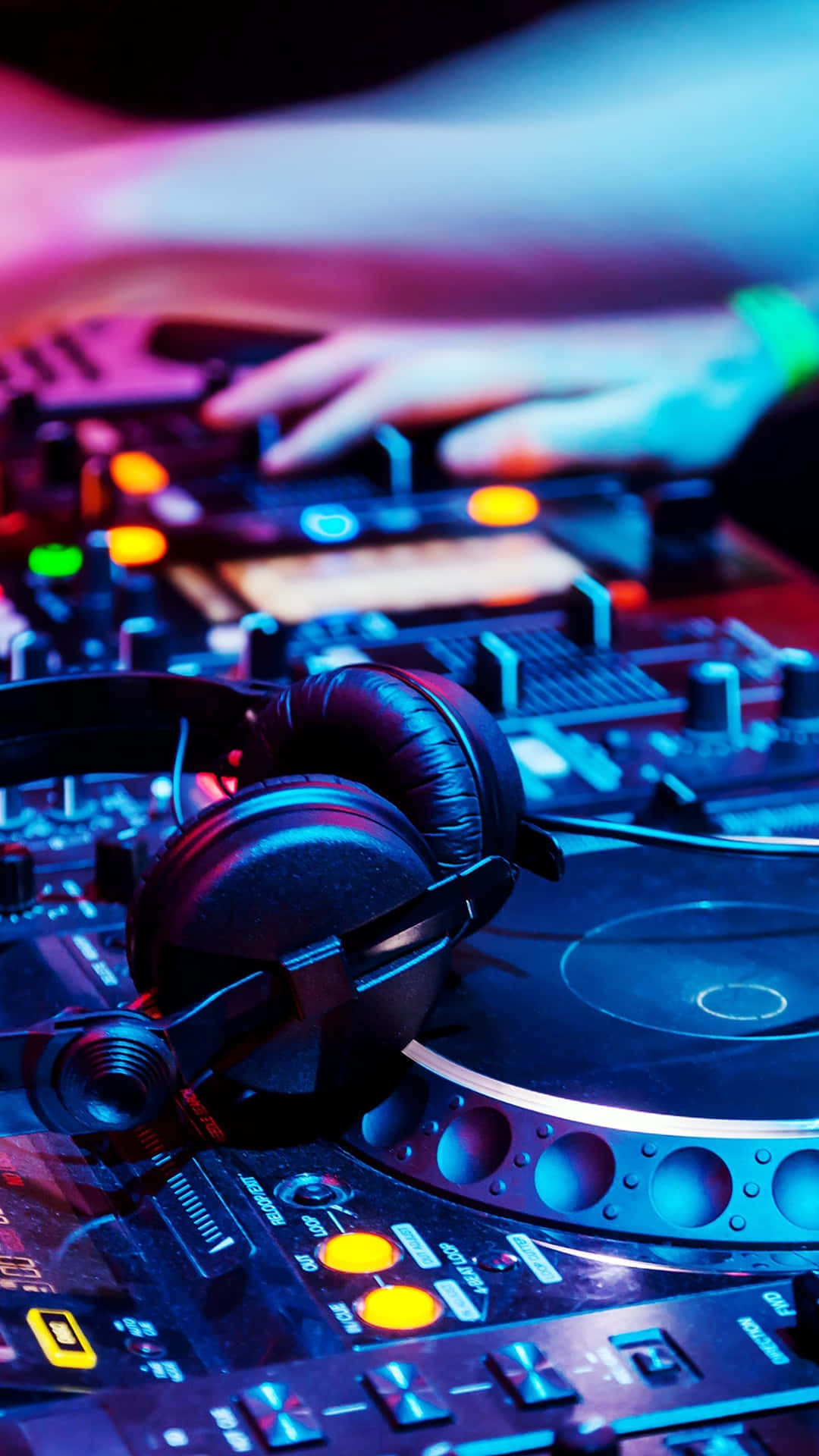 DJ的手在發光唱盤上混音，耳機在附近，背景是螢光燈光。 — DJ GIF 壁紙