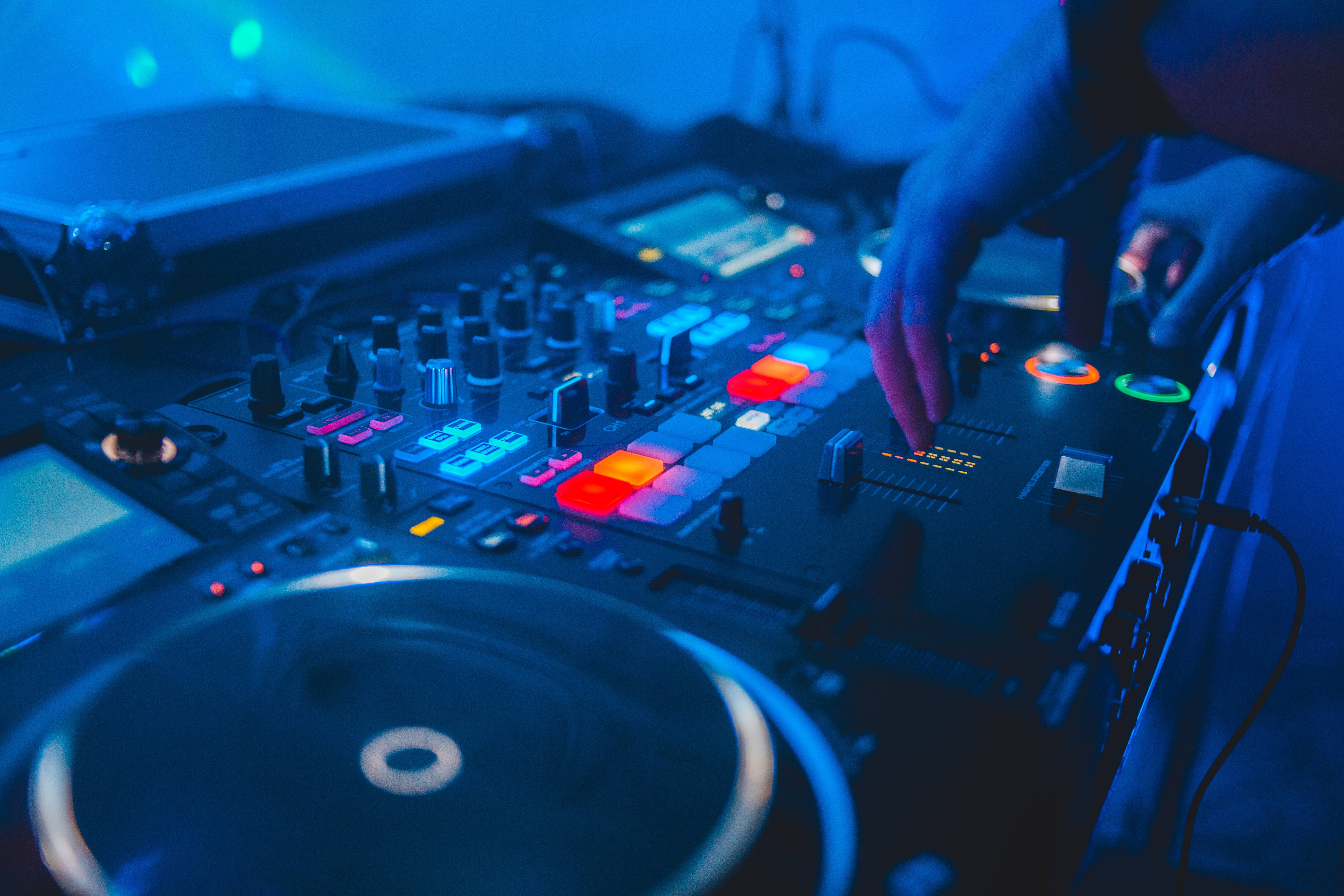 DJ 桌布 壁紙 — DJ的手在酷藍色舞台燈光下調整黑色混音器上的發光按鈕。