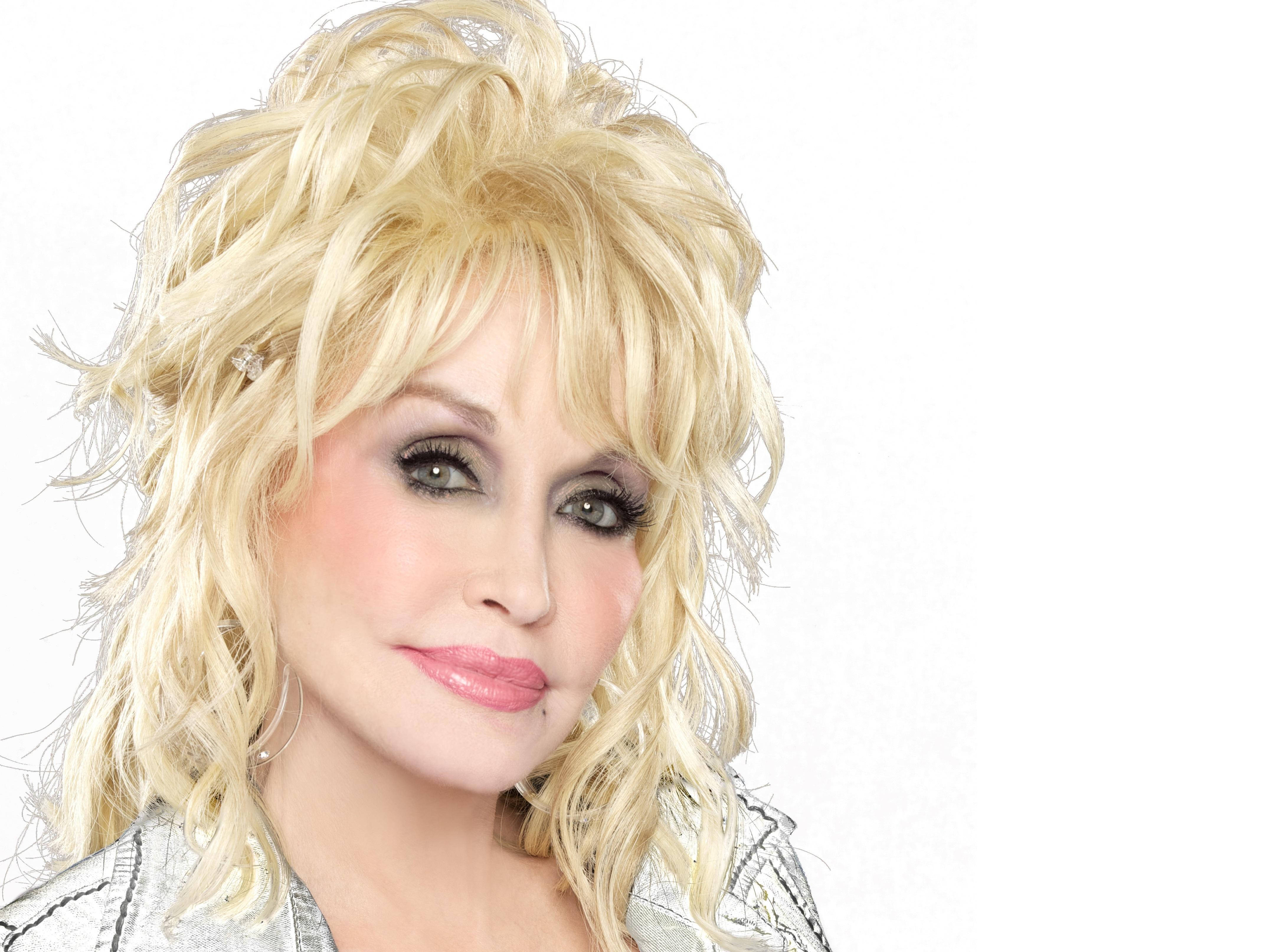 dolly 桌布 壁紙 — Dolly Parton 擁有豐盈金髮和銀色外套，背景為純白色。