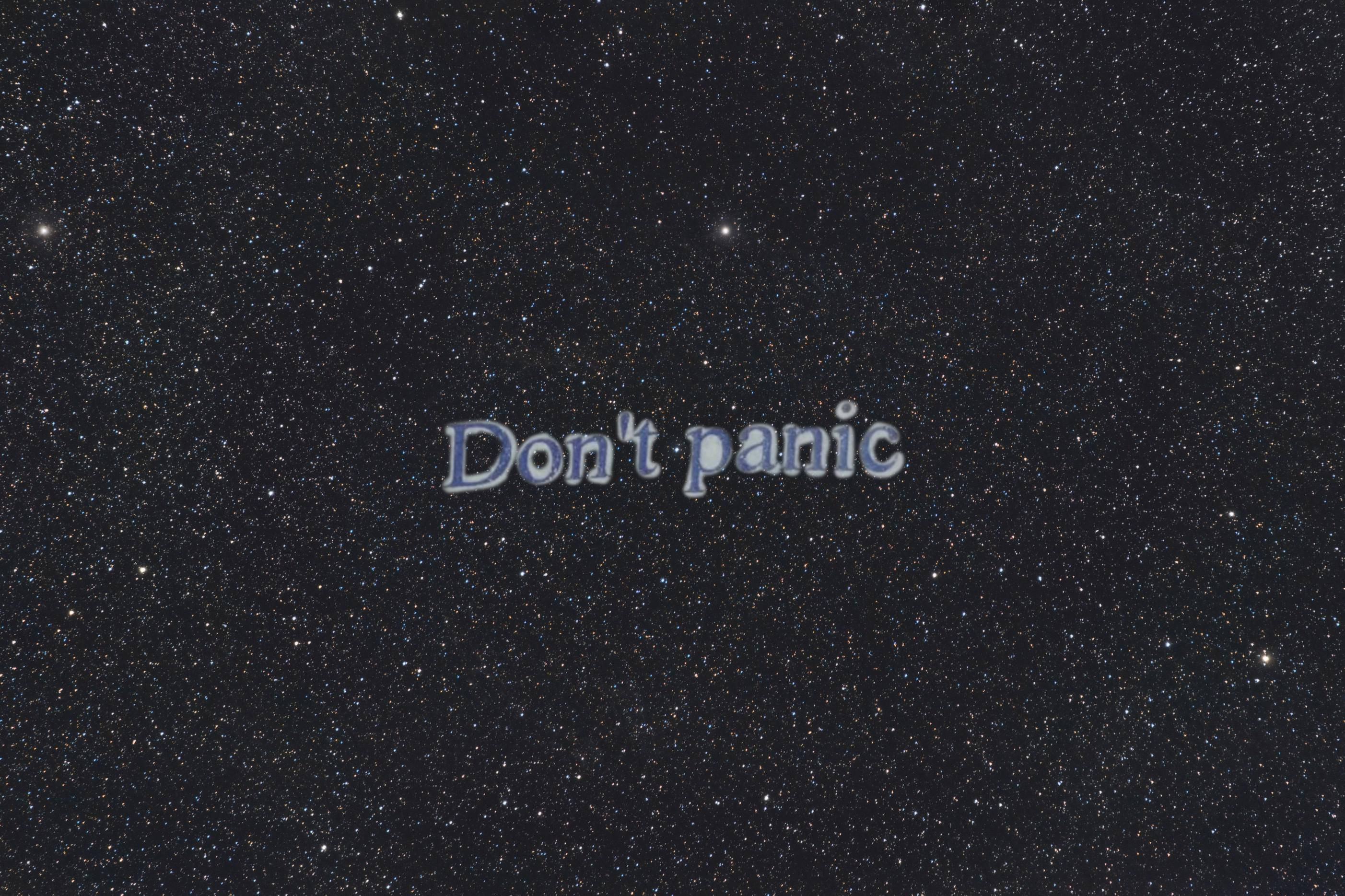 Panic 桌布 壁紙 — 「Don't panic」這個短語漂浮在一個充滿無數閃爍星星的星空夜空。