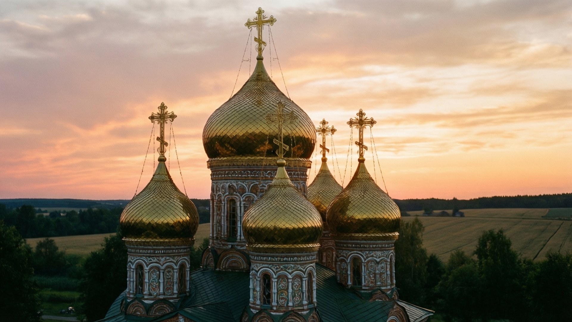 Russia 桌布 壁紙 — 東正教教堂的金色圓頂在柔和的橙色日落天空下，於起伏的綠色田野上方閃耀。