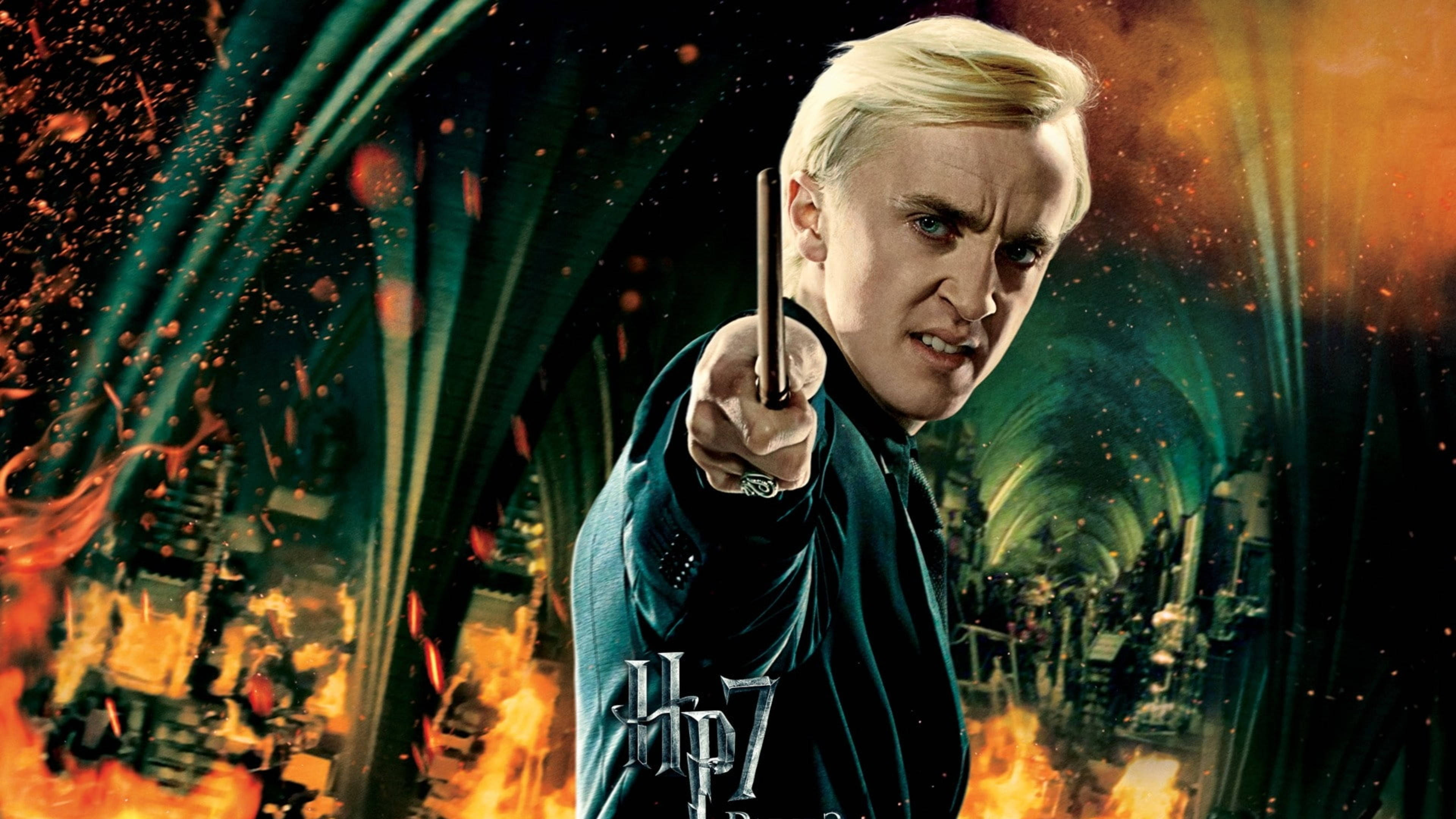 Tom 桌布 壁紙 — Draco Malfoy 兇狠地將魔杖指向前方，魔法能量和火焰在他周圍爆發，形成一個戲劇性的戰鬥場景。