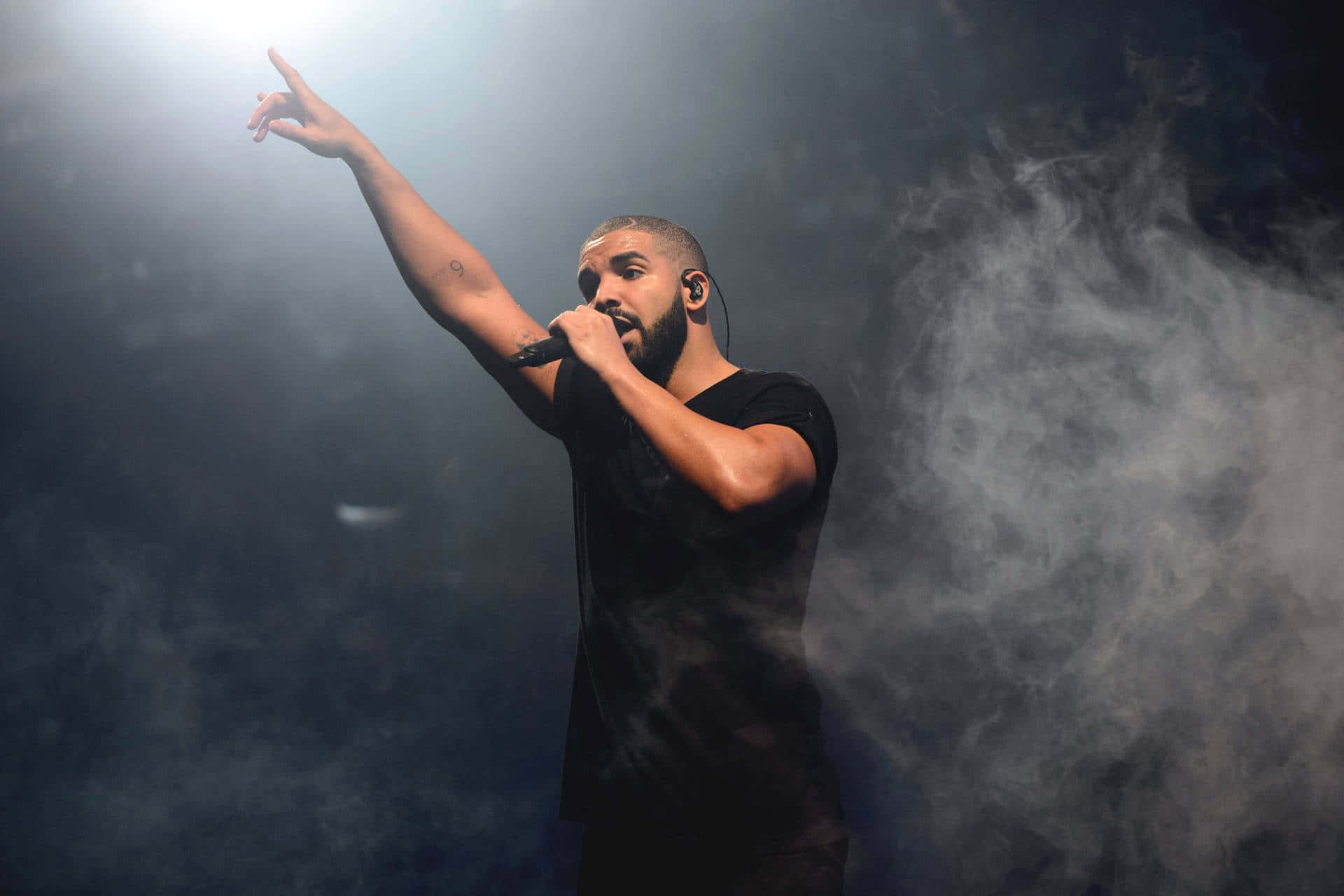 Aesthetic Drake 桌布 壁紙 — Drake 在明亮的聚光燈下表演，煙霧圍繞著他，他對著麥克風唱歌。