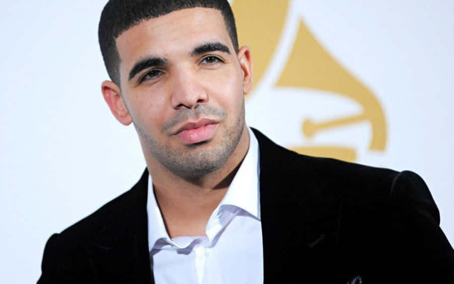 Aesthetic Drake 桌布 壁紙 — Drake 身穿黑色天鵝絨西裝和白色襯衫，在葛萊美獎背景下自信地擺姿勢。