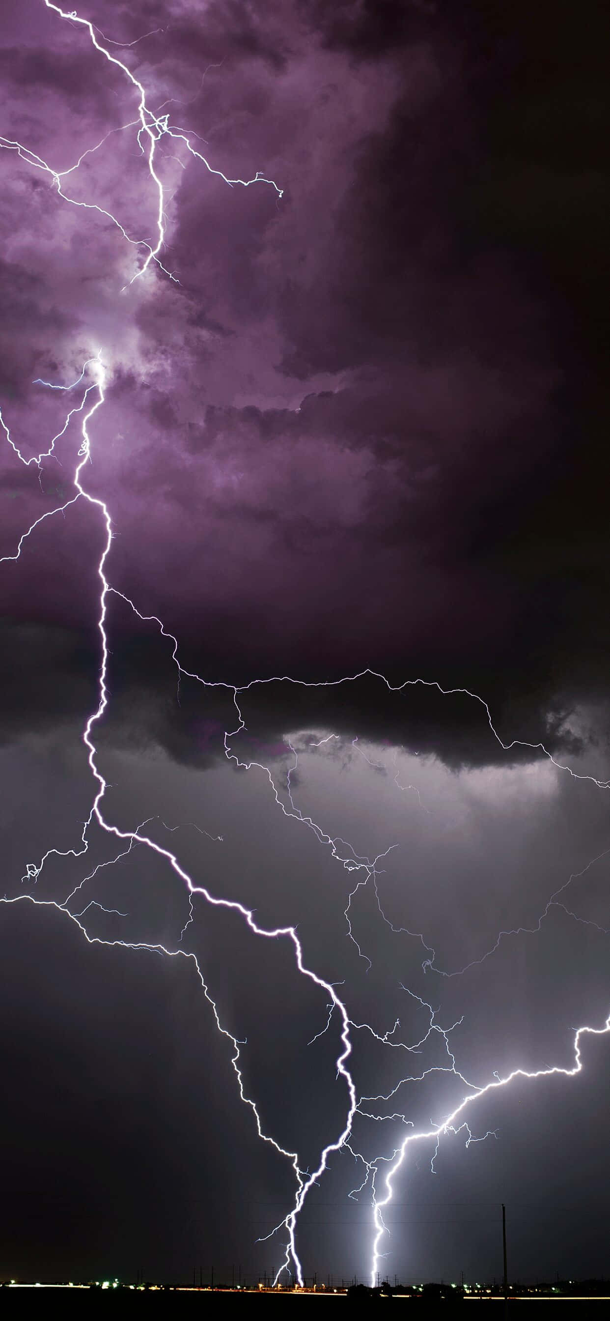 Lightning iPhone 桌布 壁紙 — 一個戲劇性的夜空被多道鮮明的閃電劈開，照亮了深紫色的暴風雲。