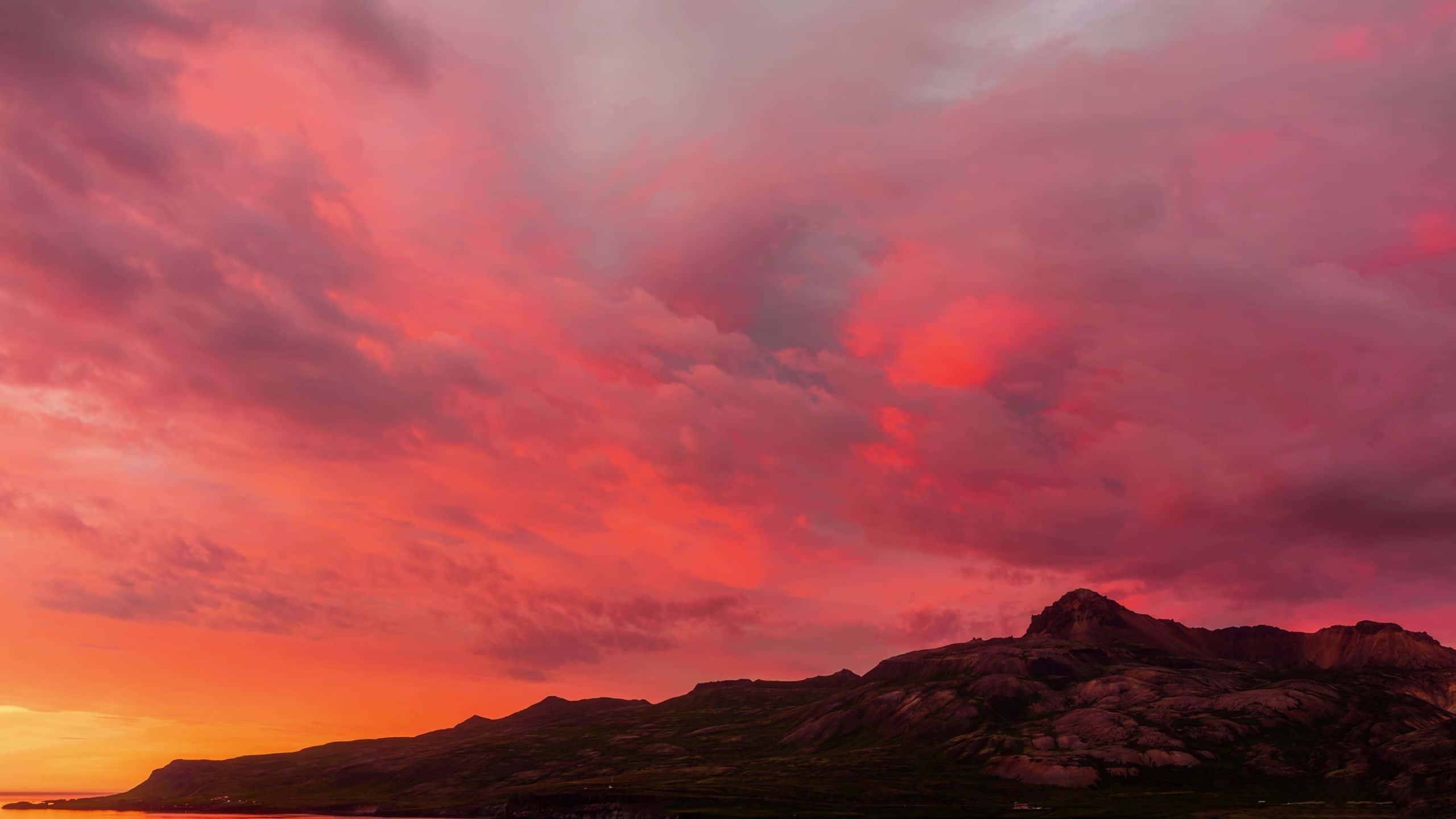 Colorful Sunset 桌布 壁紙 — 戲劇性的日落將天空染成火紅和橙色，映襯著地平線上崎嶇的山脈輪廓。