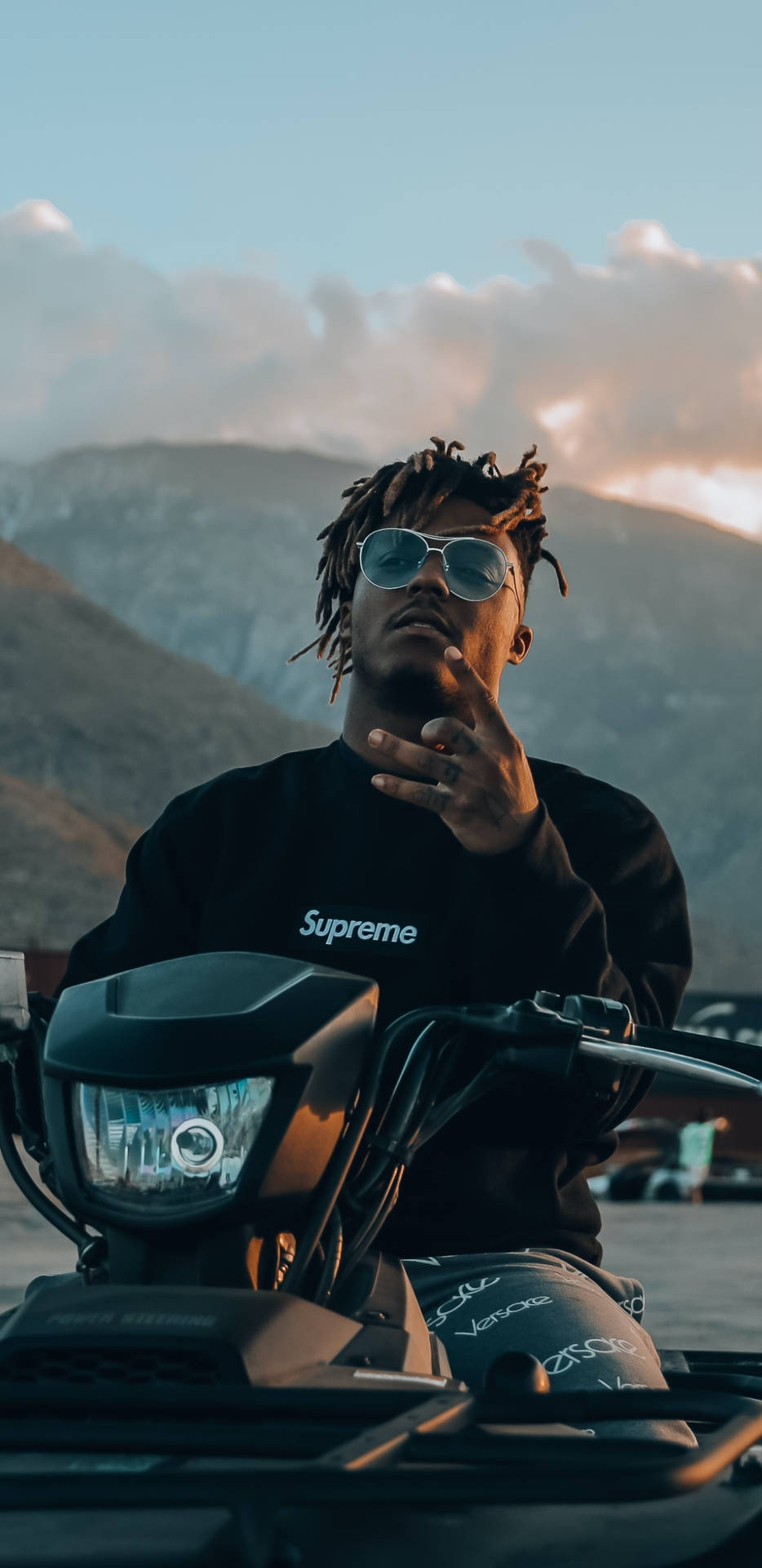 戴太陽眼鏡男子在日落山脈背景下騎摩托車 — Juice Wrld 壁紙