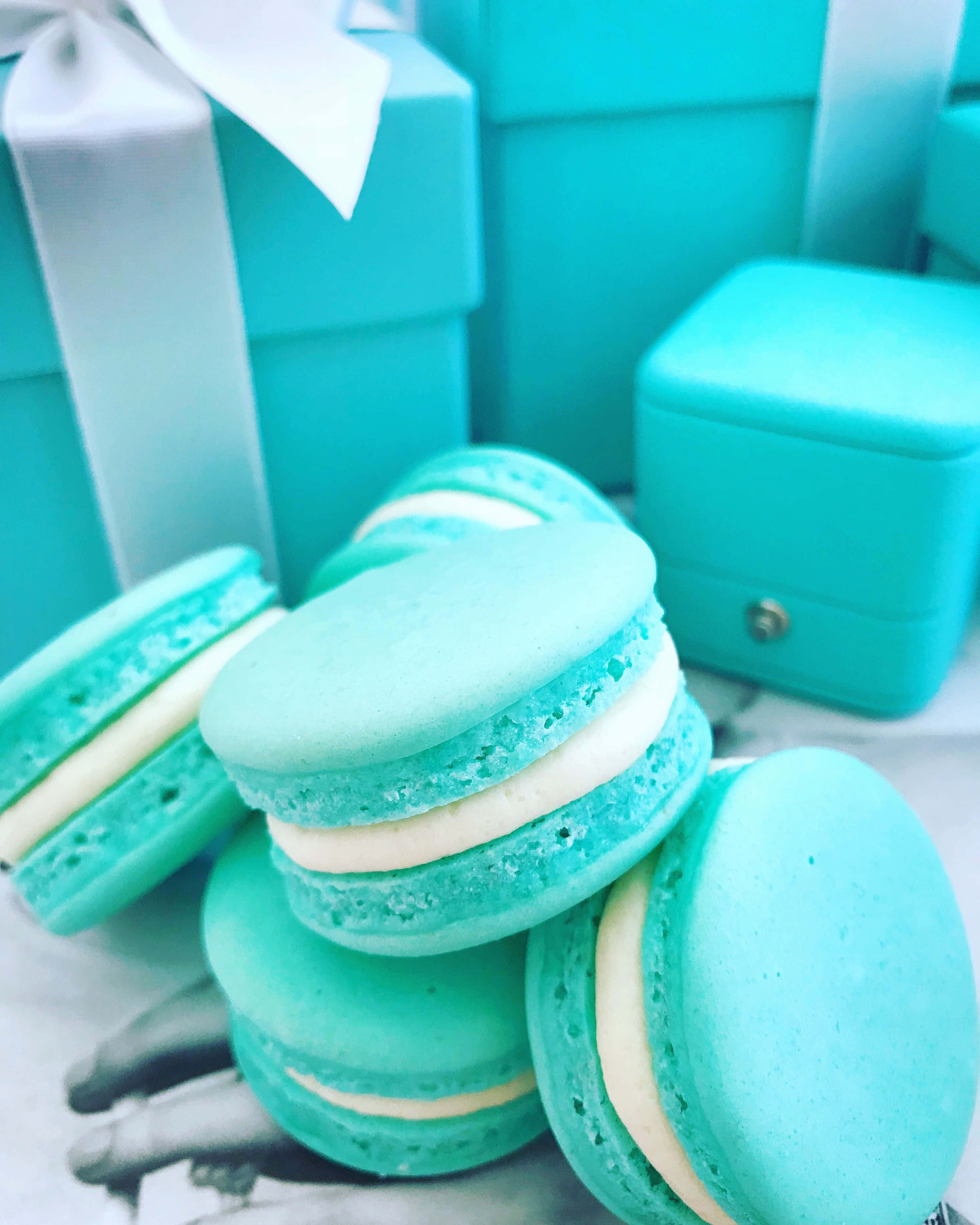 Turquoise Blue 桌布 壁紙 — 堆疊的綠松石馬卡龍搭配白色奶油，旁邊是配套的禮品盒，放置在大理石表面上。