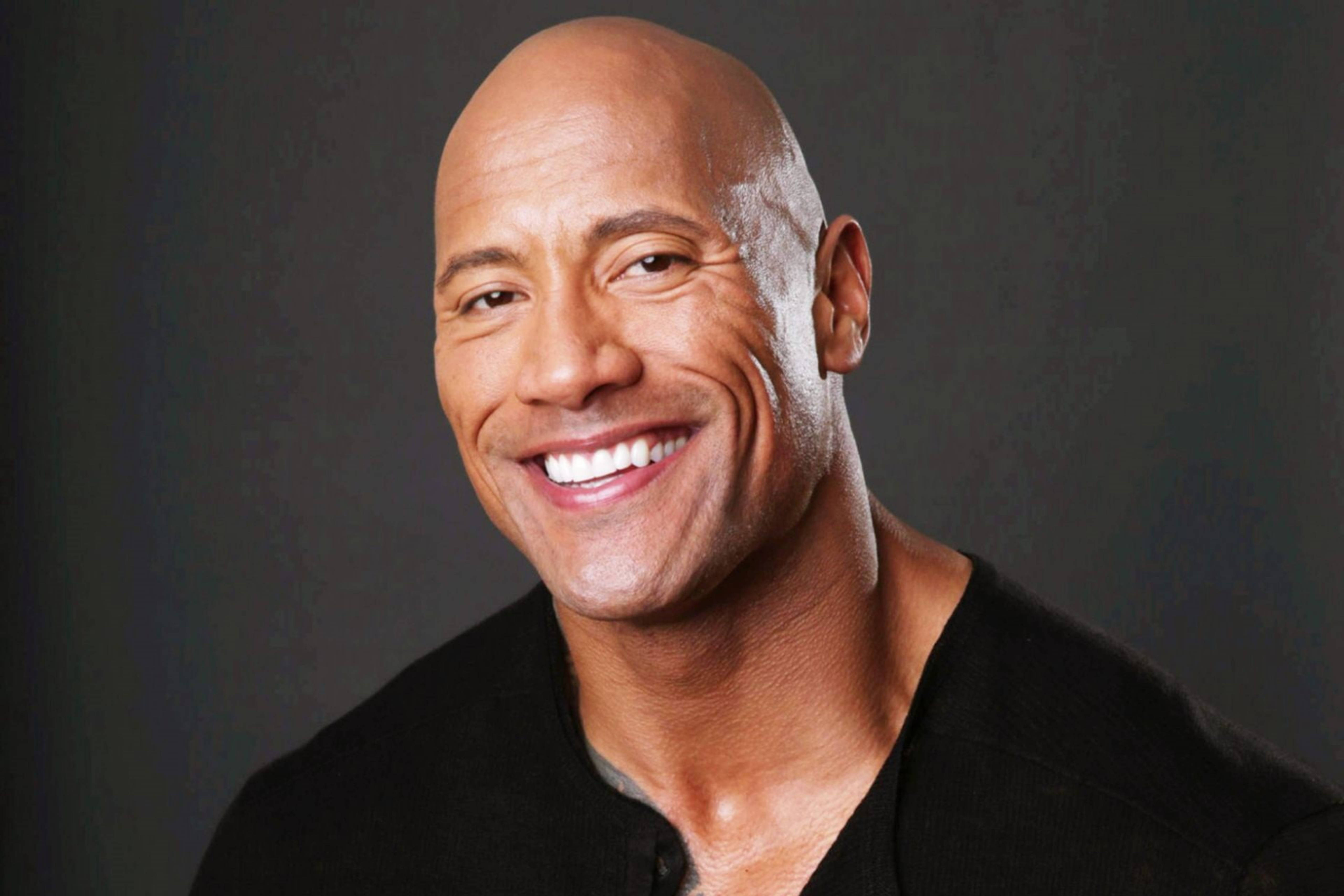 Dwayne 桌布 壁紙 — Dwayne Johnson 在深灰色工作室背景前燦爛微笑的特寫肖像。