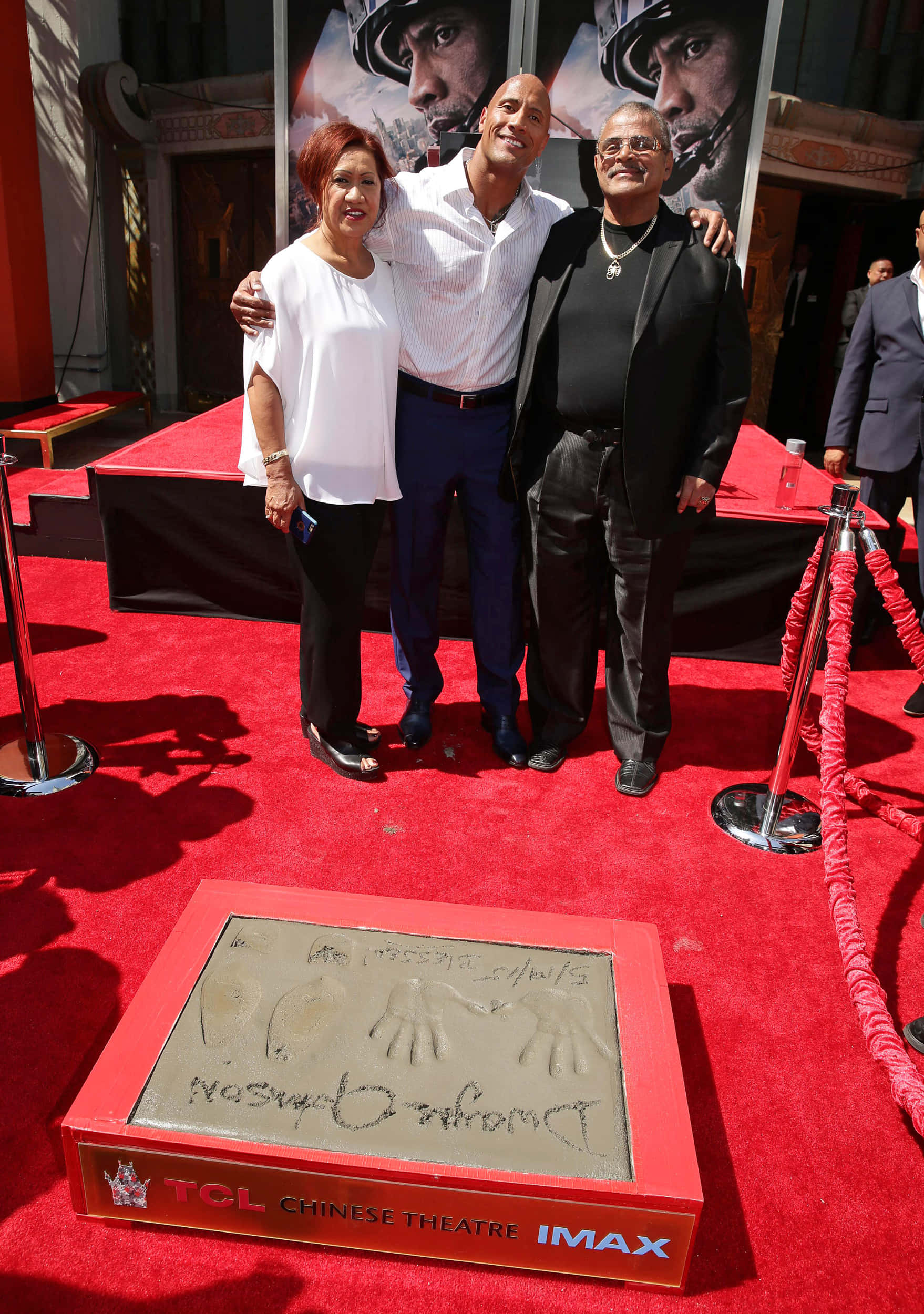 Family 桌布 壁紙 — Dwayne Johnson 在陽光普照下，與兩位嘉賓在TCL中國戲院內其手印旁的紅地毯上微笑。