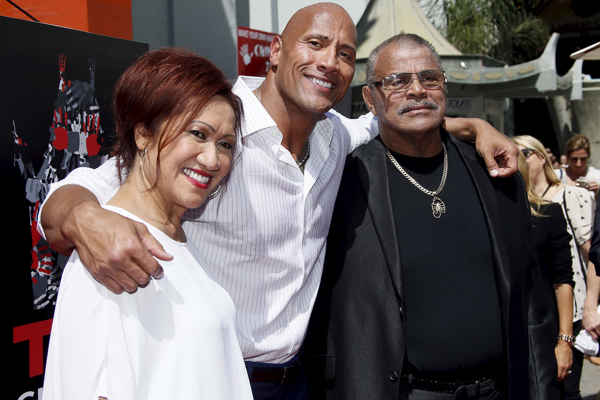 The Rock 桌布 壁紙 — Dwayne Johnson 在陽光明媚的戶外活動中與兩名男子一起露出燦爛笑容，姿勢隨意。