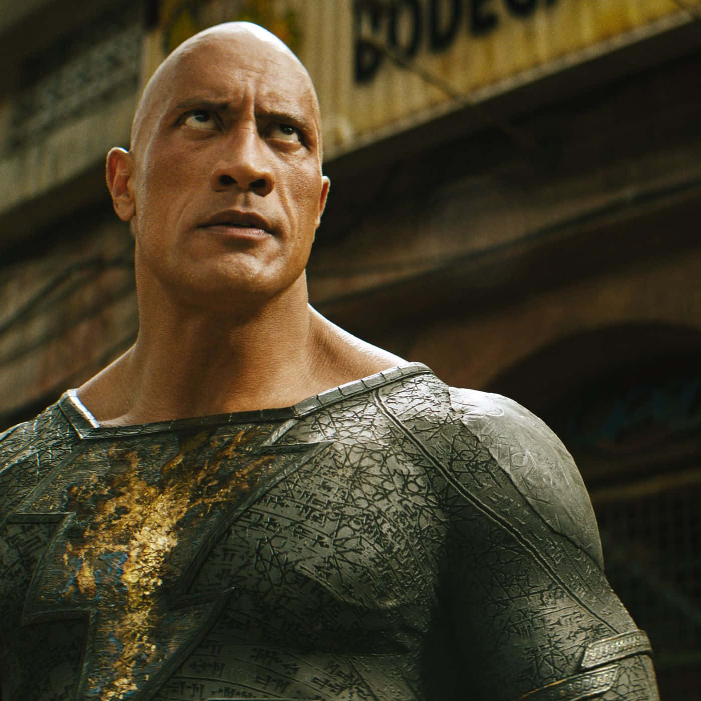 超級英雄 桌布 壁紙 — Dwayne Johnson 飾演 Black Adam，身穿破舊盔甲服裝，站在粗糙的城市小巷中，表情堅定。