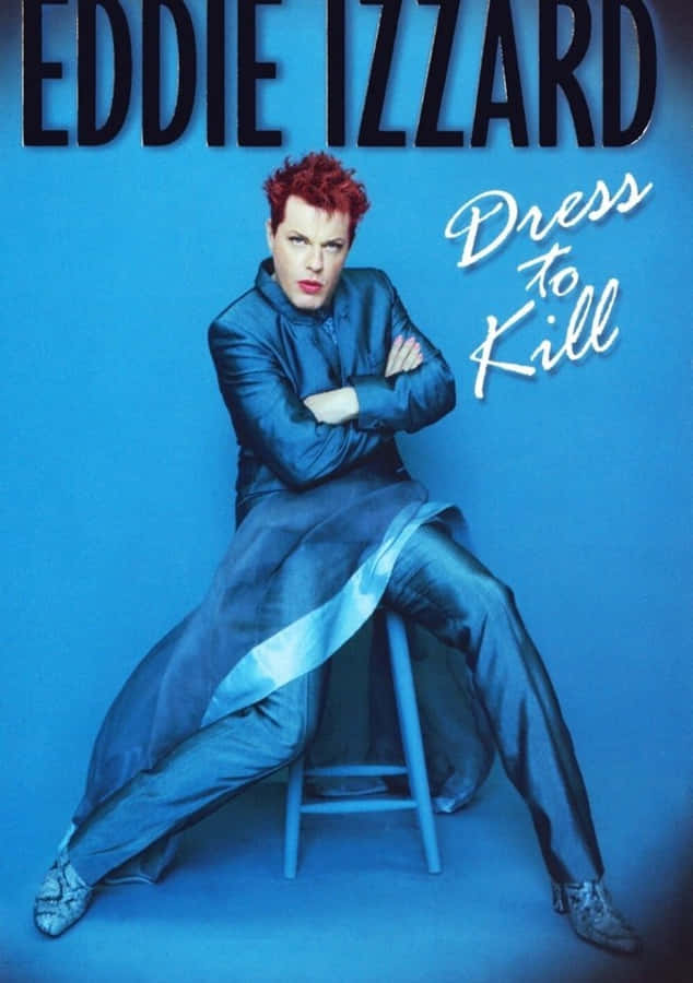 Eddie Izzard 桌布 壁紙 — Eddie Izzard 自信地坐在凳子上，身穿時尚藍色服裝，背景為純藍色並帶有粗體文字。
