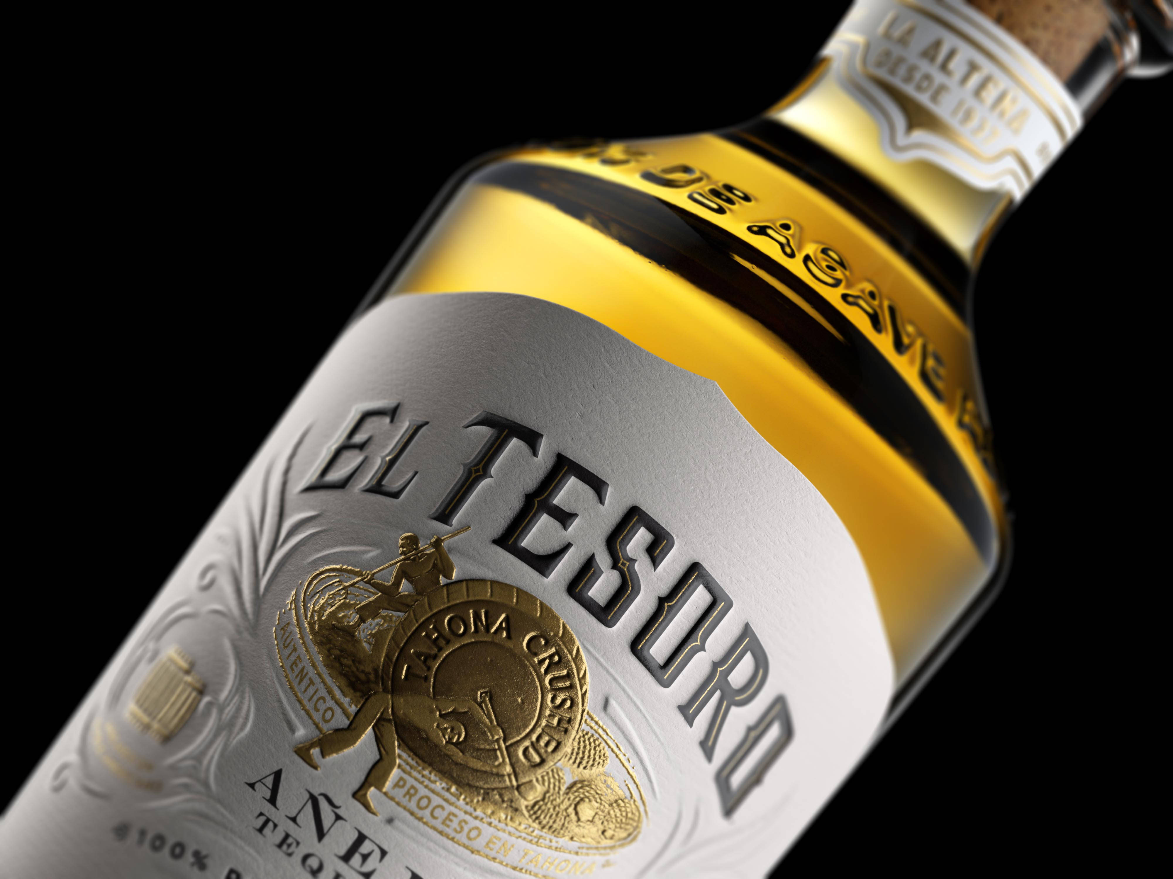 alcohol 桌布 壁紙 — El Tesoro 龍舌蘭酒瓶特寫，金色和銀色標籤細節，黑色背景。