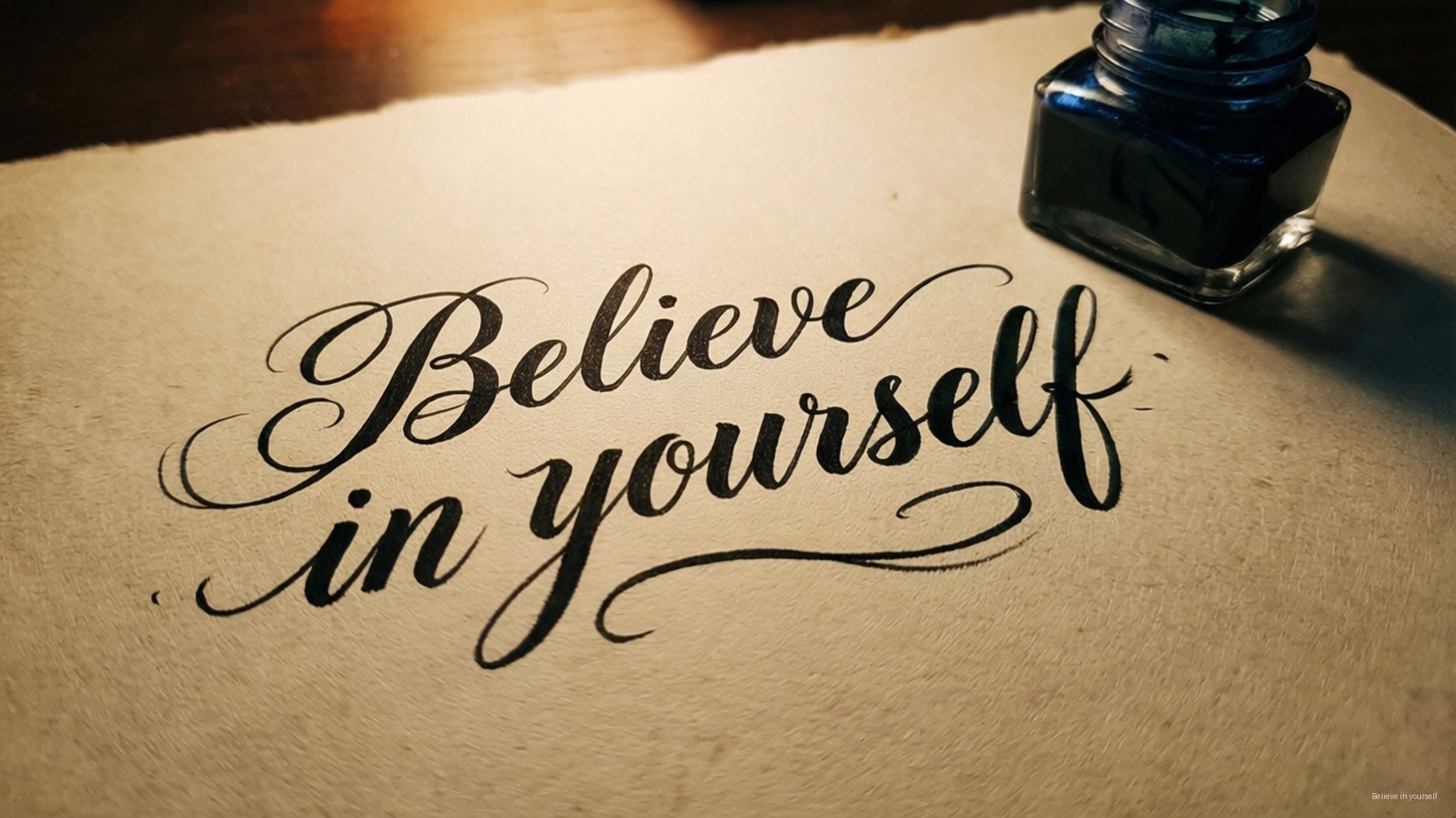 Believe Calligraphy 壁紙 — 優雅的黑色書法，在質感米色紙上寫著「相信自己」，旁邊有一個藍色墨水瓶。