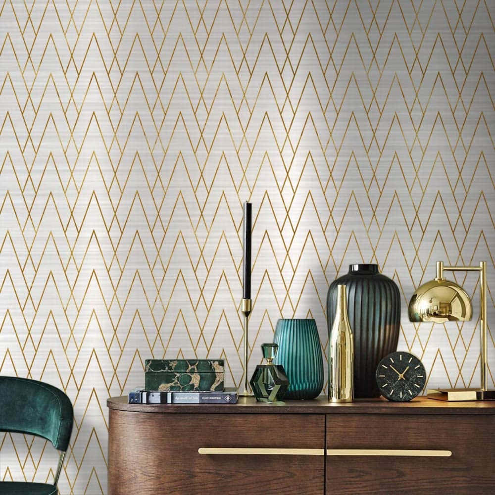  壁紙 — 優雅的金色鋸齒紋壁紙，搭配現代裝飾，包括綠色天鵝絨椅子和木製控制台上的黃銅燈。