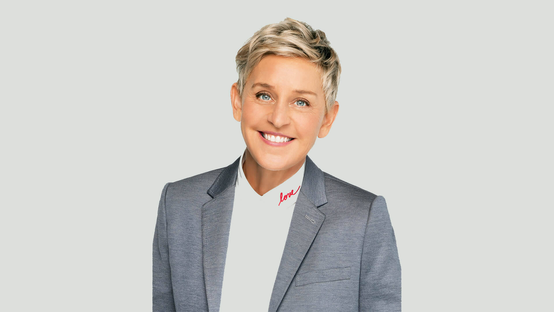 艾倫·狄珍妮 桌布 壁紙 — Ellen DeGeneres 穿著灰色西裝外套搭配白色高領毛衣，紅色草書文字，溫暖地微笑。