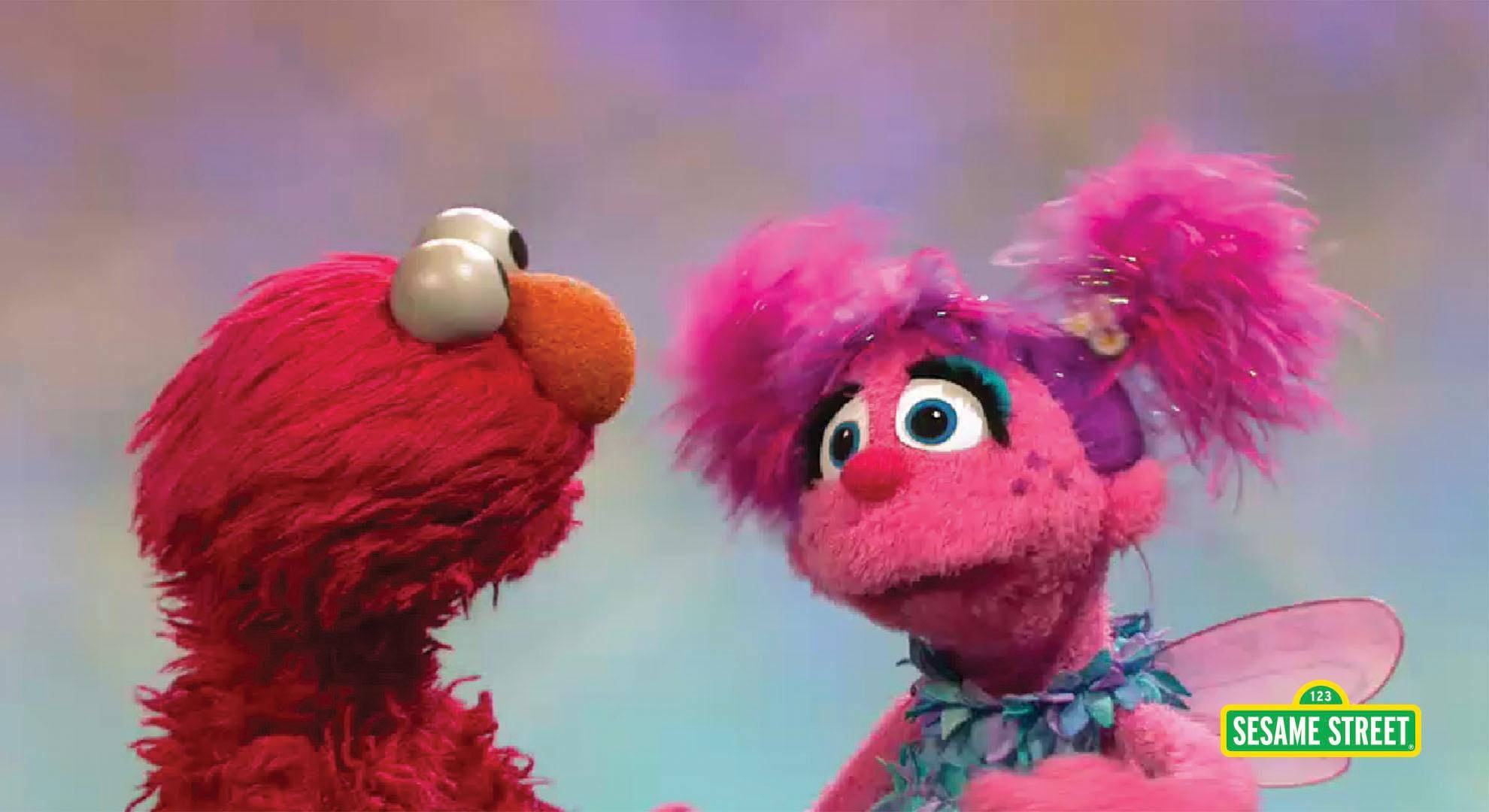 Elmo 桌布 壁紙 — Elmo 和 Abby Cadabby 在柔和粉彩天空背景下，以明亮的眼睛對視。