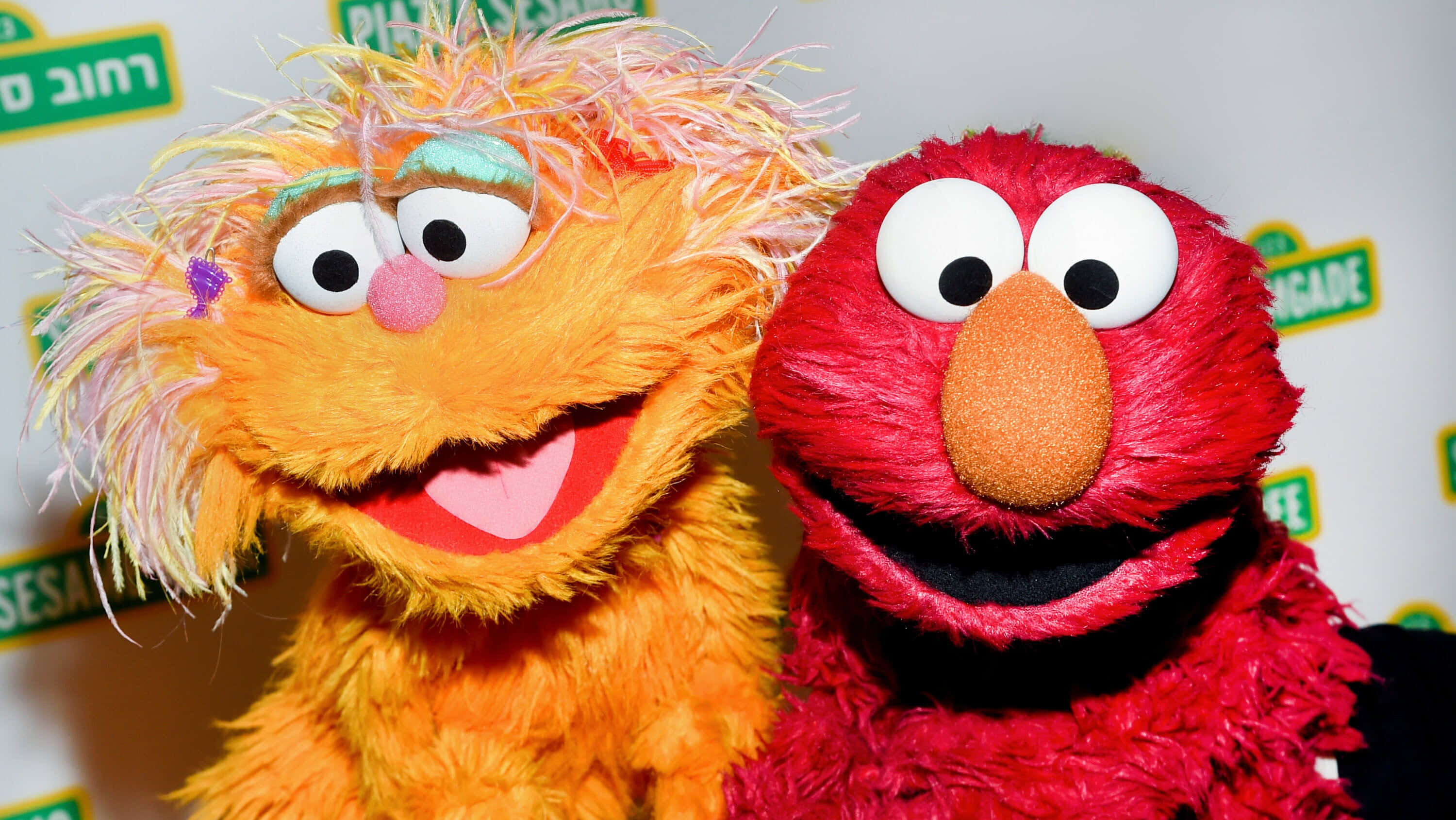Elmo 桌布 壁紙 — Elmo 和一個毛茸茸的橙色 Muppet 在芝麻街背景下燦爛地微笑。