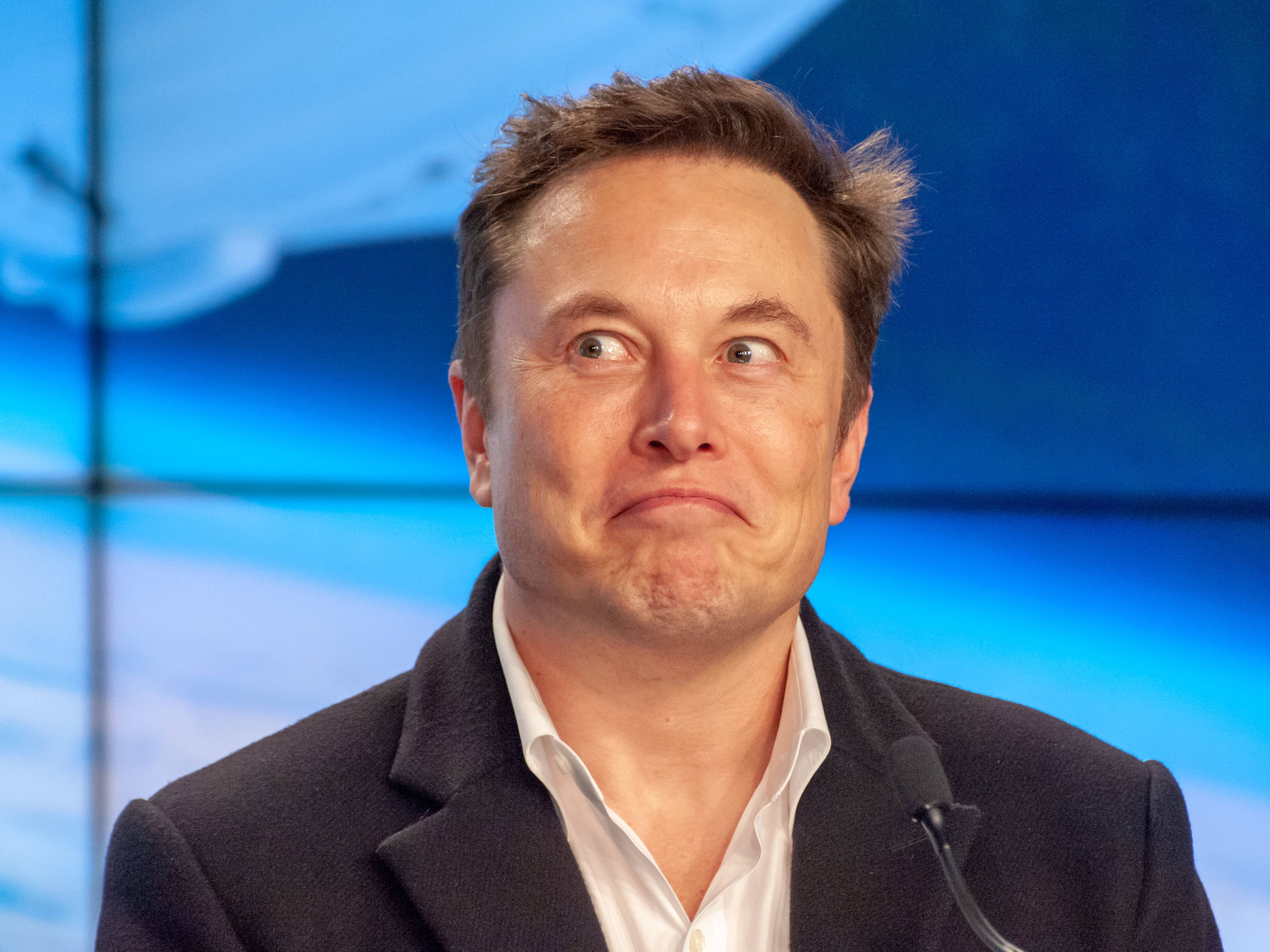 Elon 桌布 壁紙 — Elon Musk 在藍色抽象背景的新聞發布會上說話時做出鬼臉。