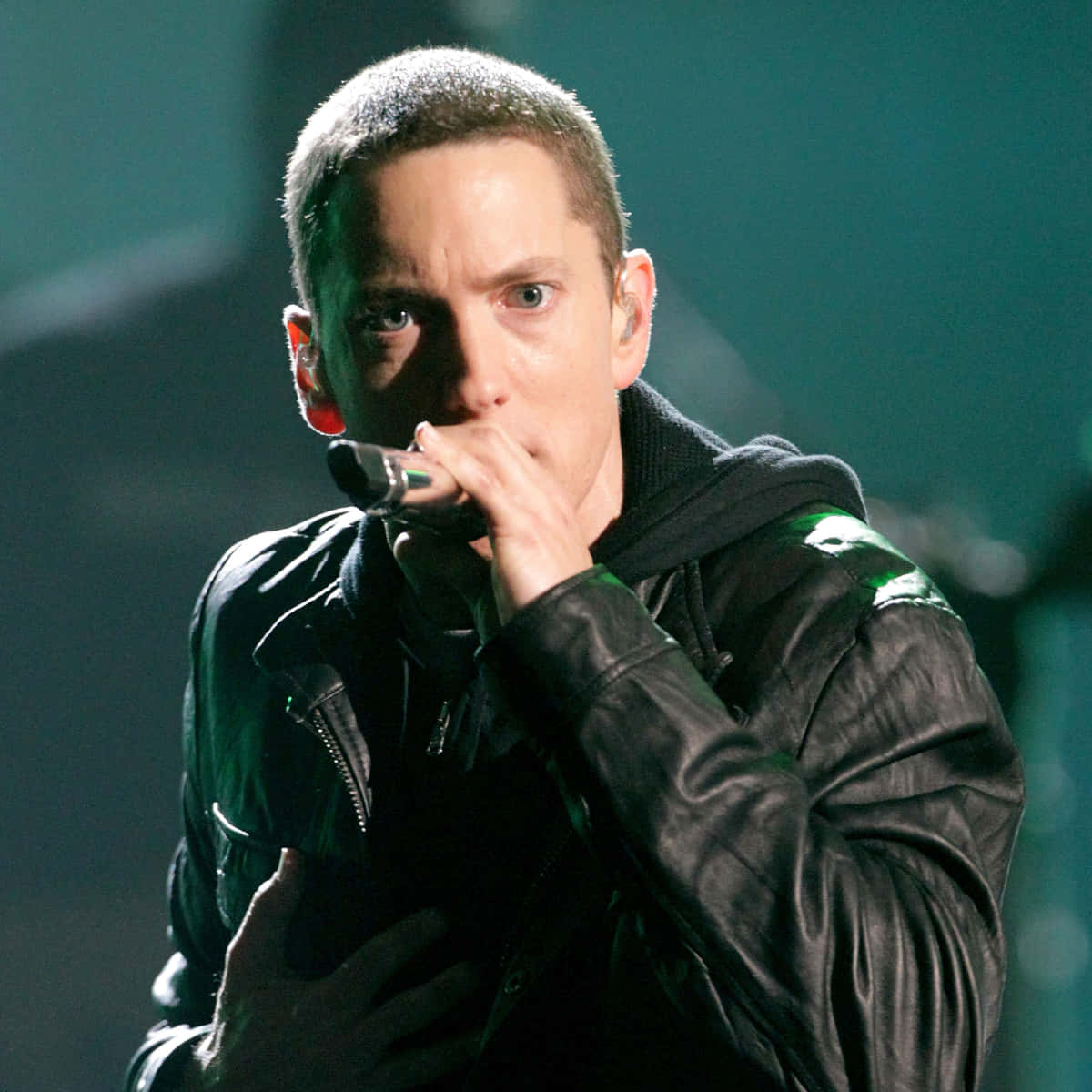 阿姆 桌布 壁紙 — Eminem 在綠色舞台燈光下穿著黑色皮夾克在舞台上表演的特寫。