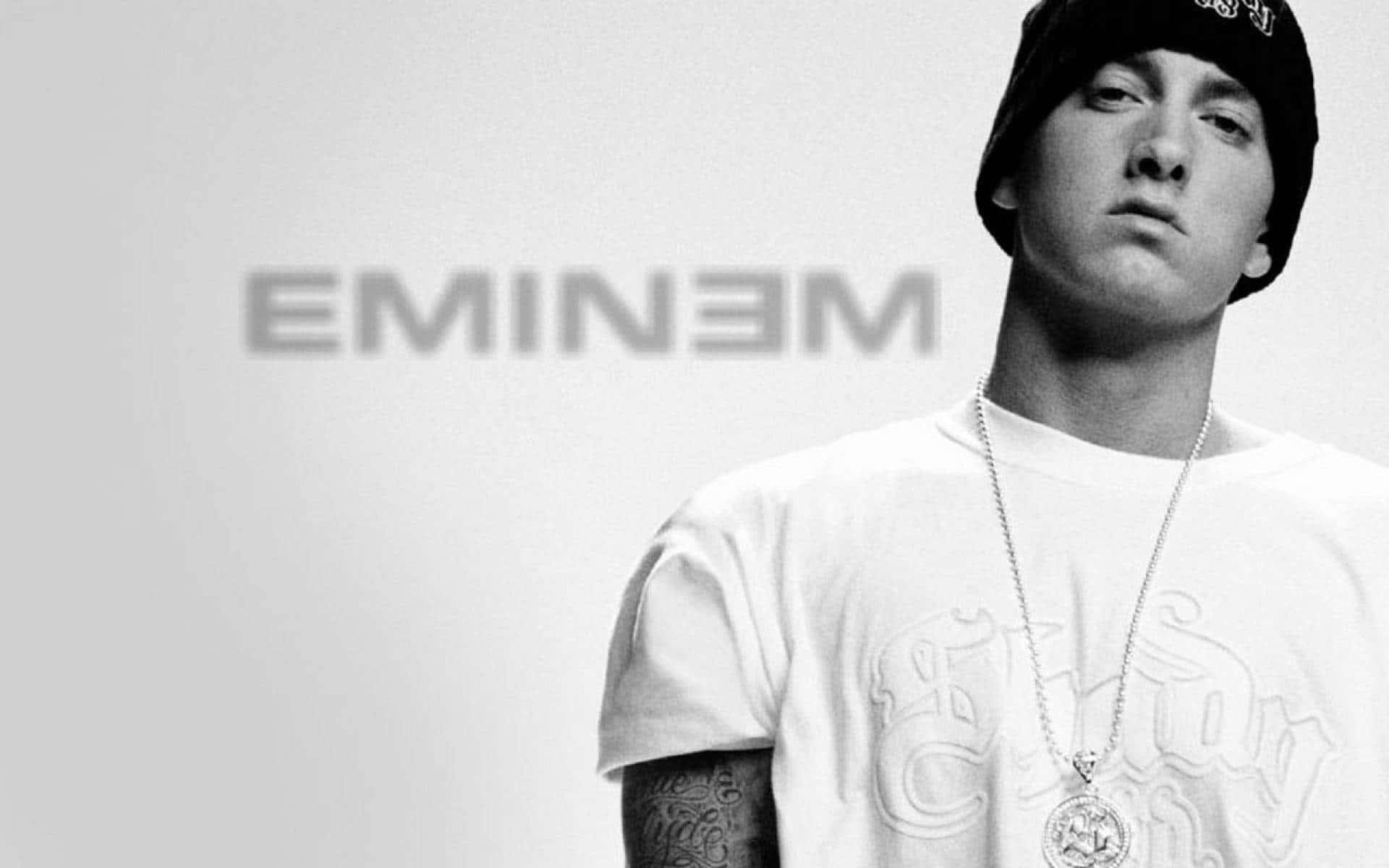 阿姆 桌布 壁紙 — Eminem 的黑白肖像，戴著毛帽和鏈條，背景簡潔，他的名字模糊地出現在身後。