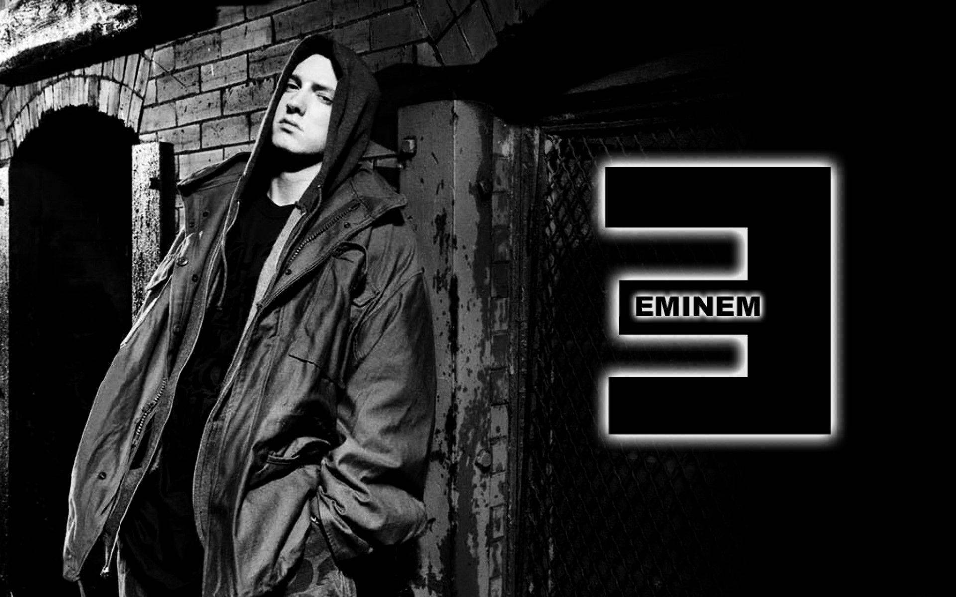 阿姆 桌布 壁紙 — Eminem 站在一條骯髒的小巷中，身穿連帽外套，他標誌性的「3」標誌在他旁邊以鮮明的黑白發光。