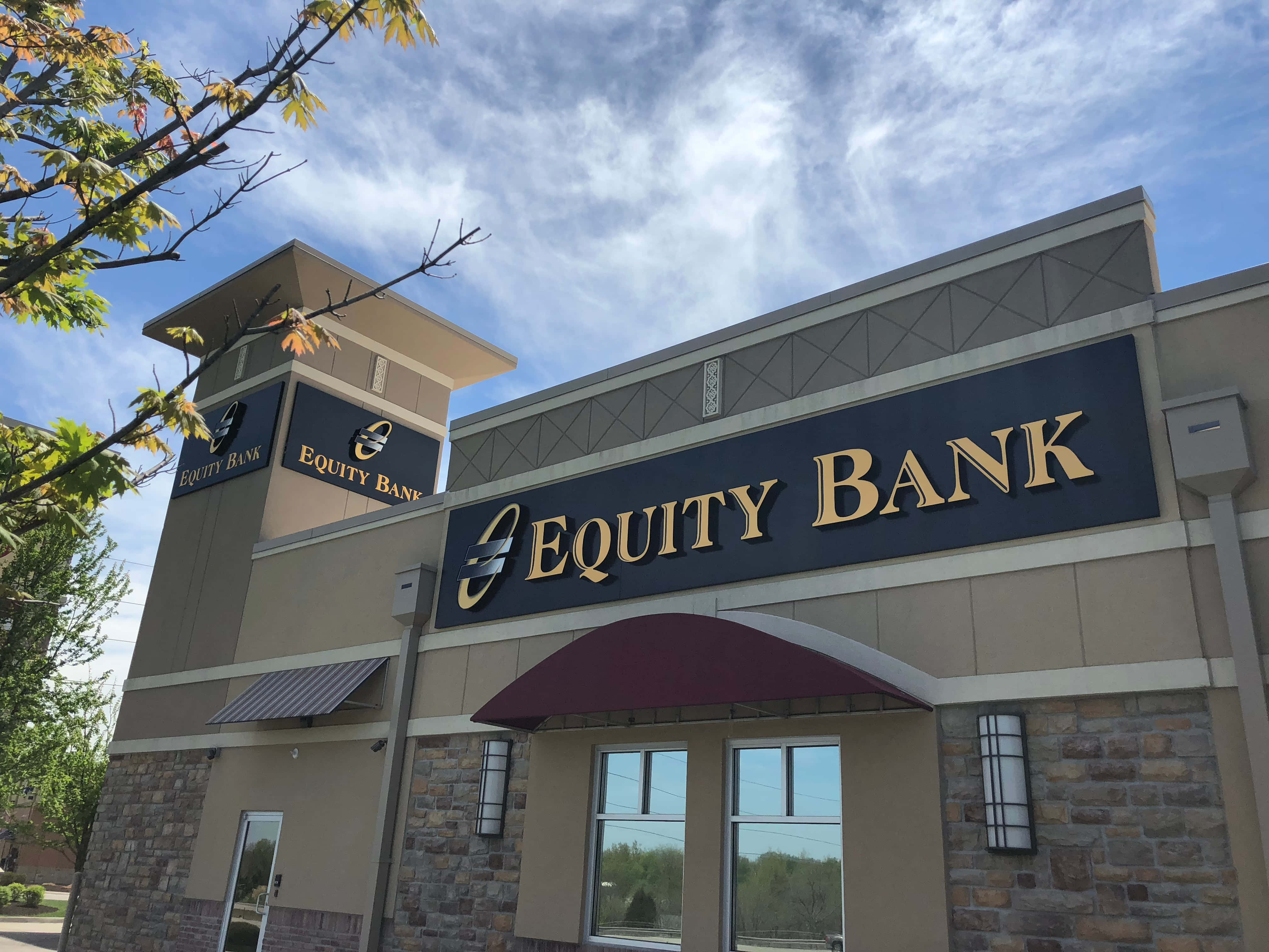 Bank 桌布 壁紙 — Equity Bank 大樓，金色字體，藍天白雲，秋葉點綴畫面邊緣。