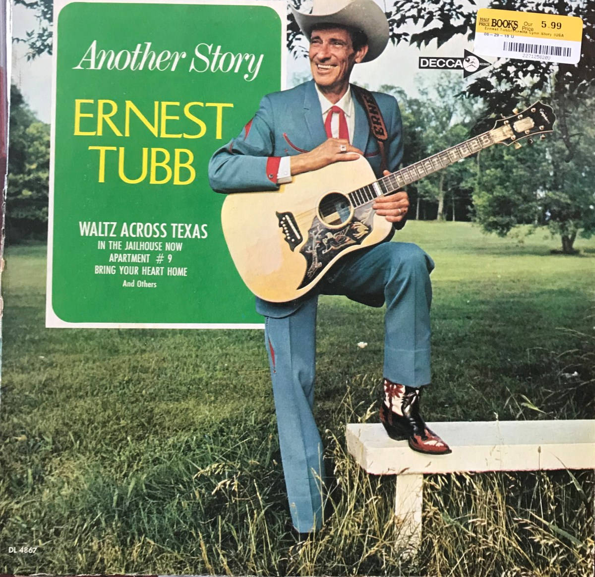 Singer 桌布 壁紙 — Ernest Tubb 微笑著，手持吉他，坐在草地上的一張長椅上，旁邊有一個綠色專輯封面。