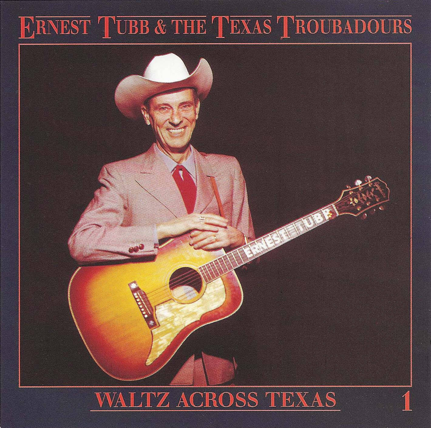 復古 桌布 壁紙 — Ernest Tubb 身穿粉紅色西裝、戴白色牛仔帽，在深色背景前溫暖微笑，手持一把旭日紋原聲吉他。