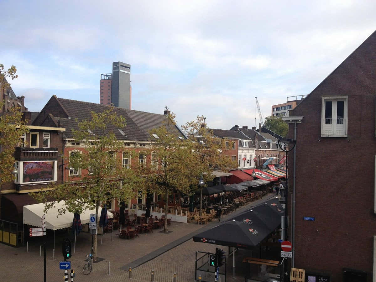 Tilburg 桌布 壁紙 — 一個歐洲城市廣場，有磚造建築、戶外咖啡館，以及一座在陰天可見的高層現代塔樓。