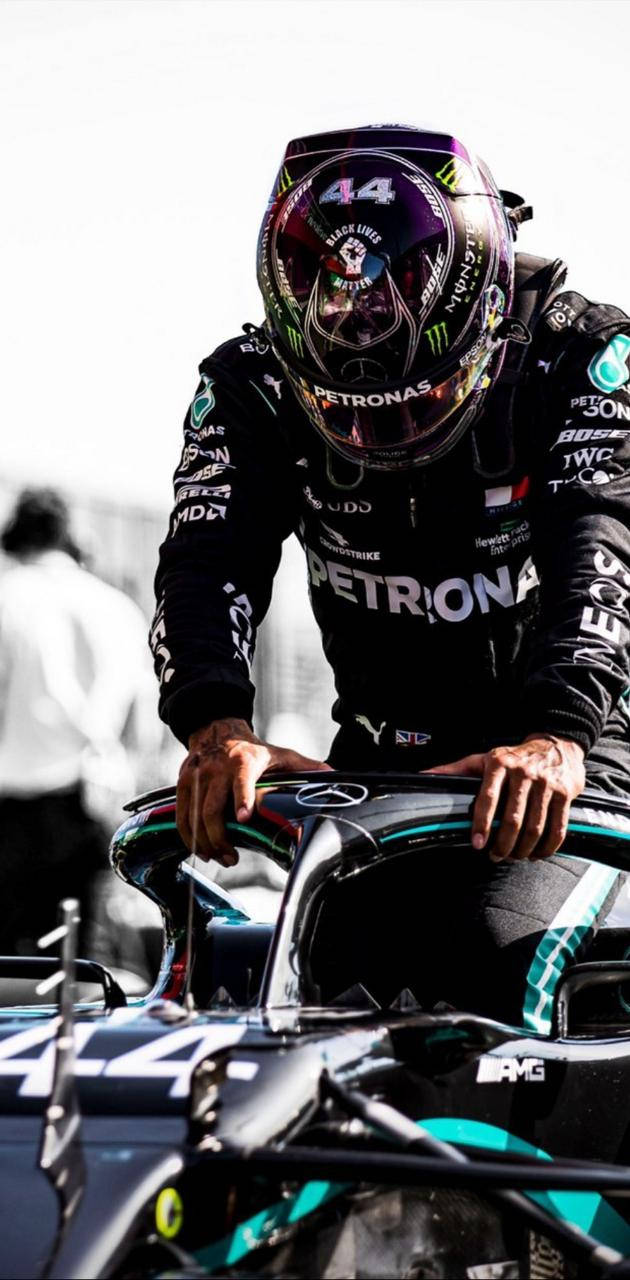 身穿賽車服的F1車手俯身靠在方向盤上 — F1 壁紙