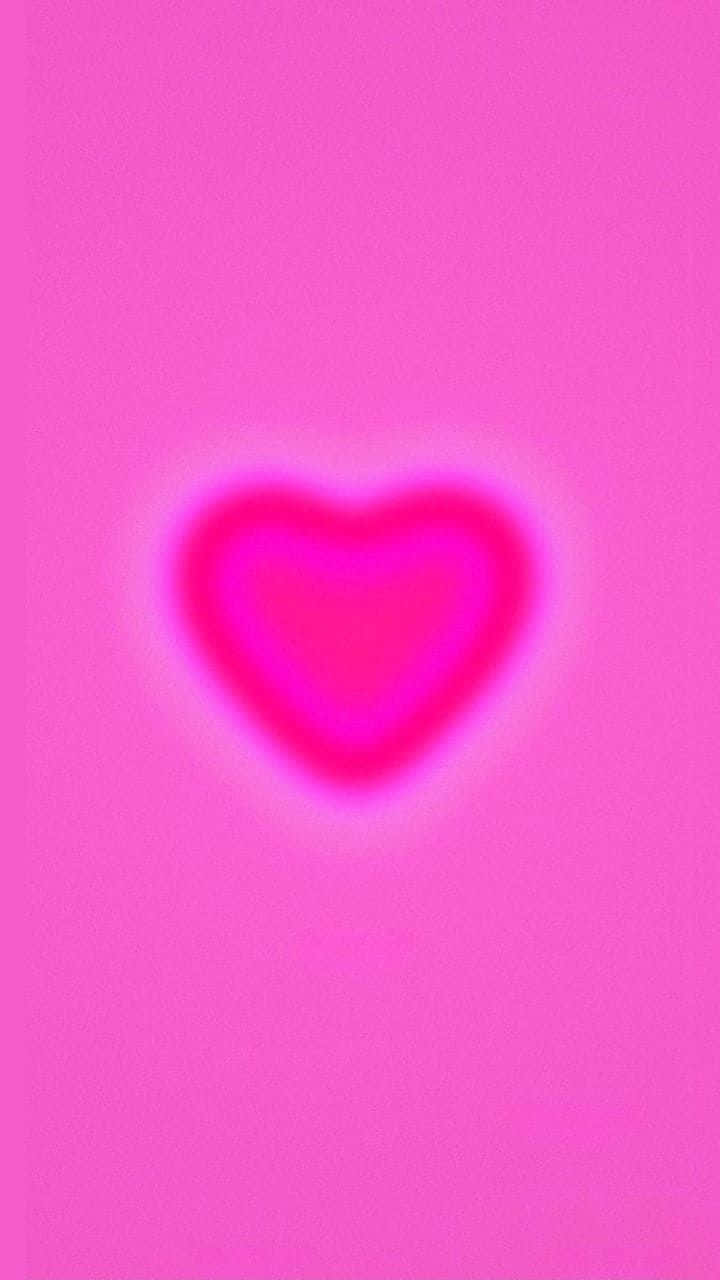 Pink Heart Aura 桌布 壁紙 — 一個發光的心形在帶有細微紋理的純粉紅色背景上散發出柔和粉紅光。