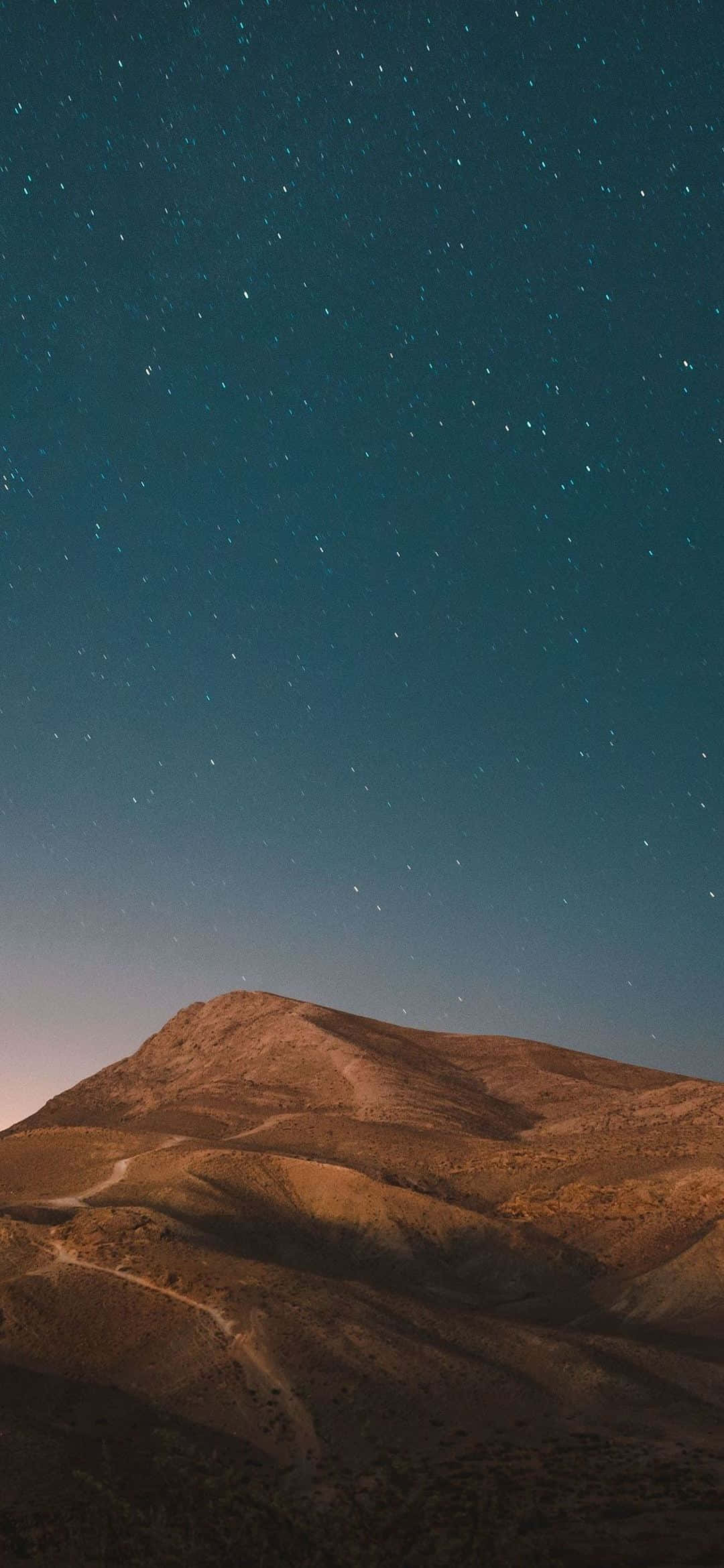 黃昏時分沙漠山脈上空的繁星夜空。 — iPhone 13 Pro 壁紙