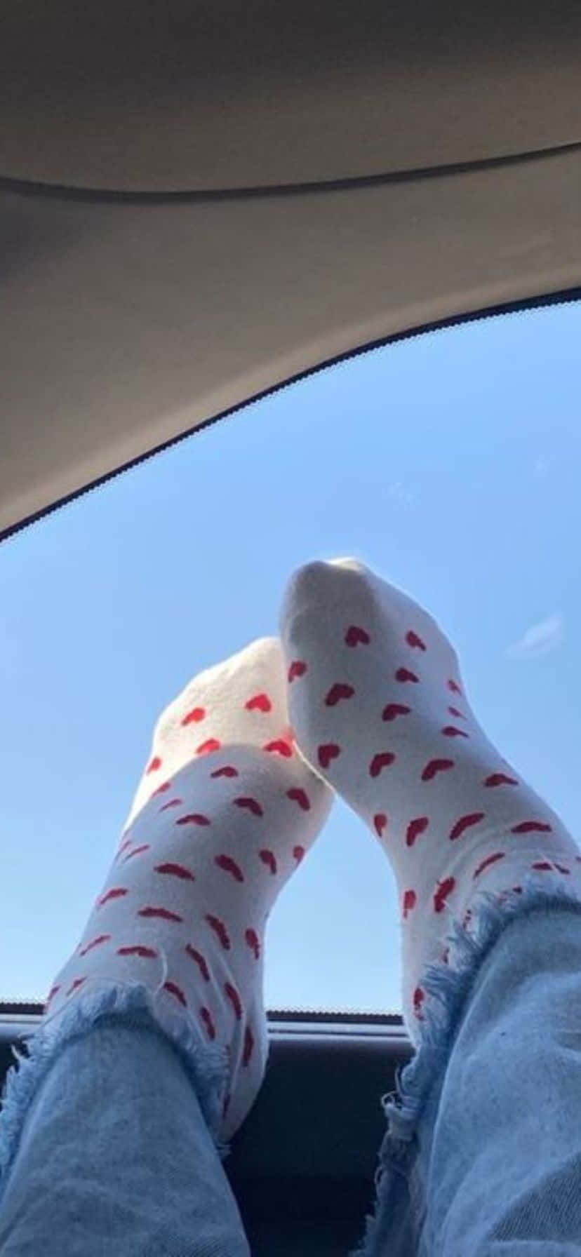  壁紙 — 穿著心形圖案襪子的腳靠在車窗上，背景是晴朗的藍天。