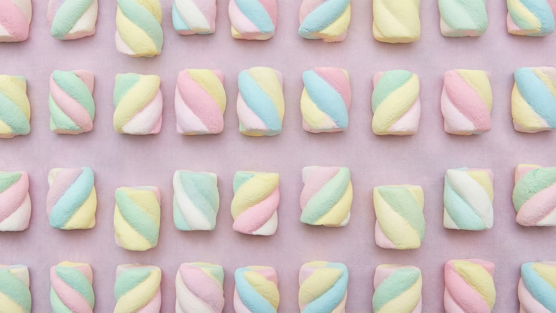 Marshmallow Pattern Fabric 壁紙 — 粉彩彩虹漩渦棉花糖整齊排列在柔軟的粉紅色背景上。