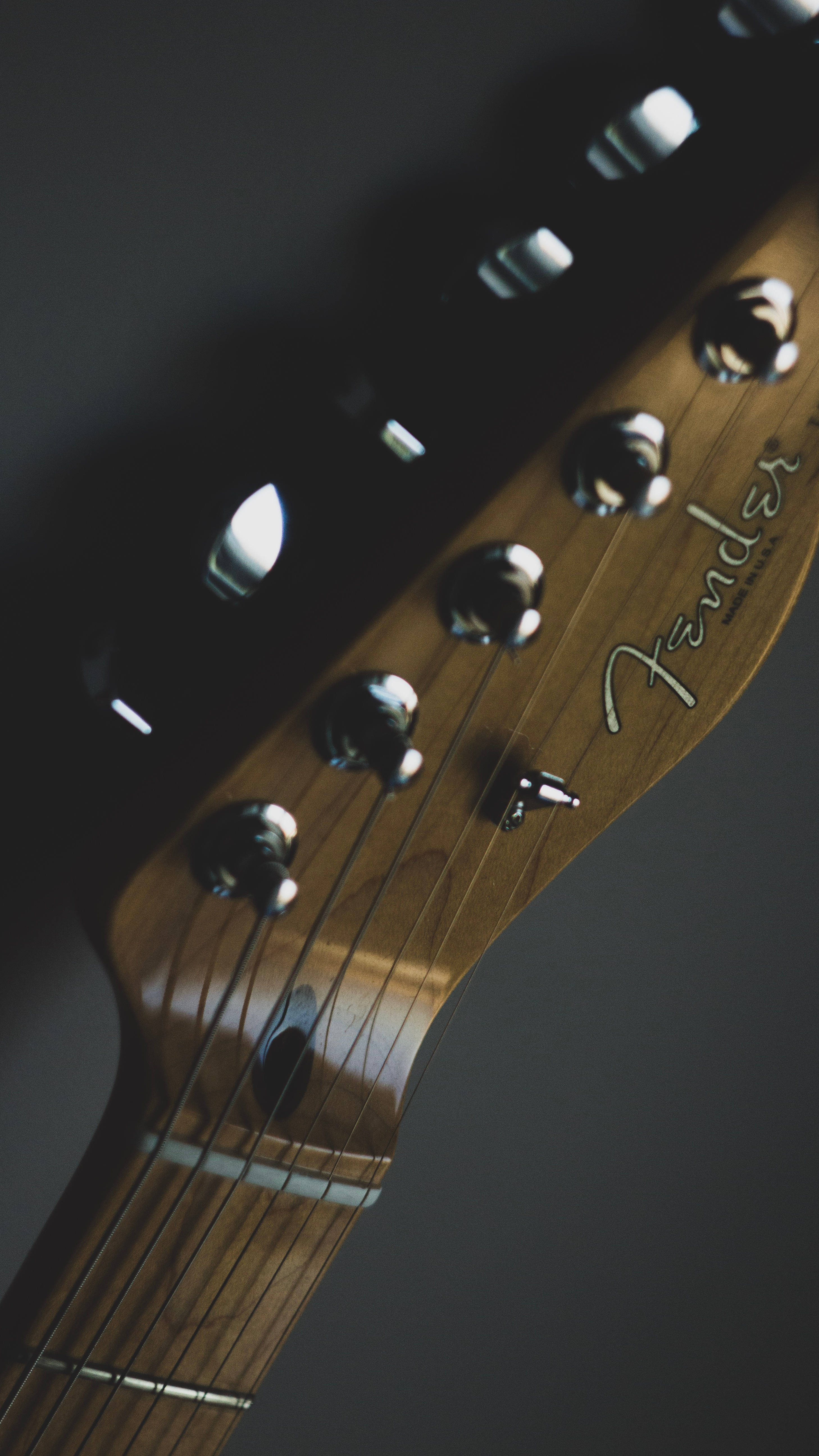high 桌布 壁紙 — Fender 吉他琴頭特寫，帶有鉻合金調音栓和木紋，在柔和燈光下。