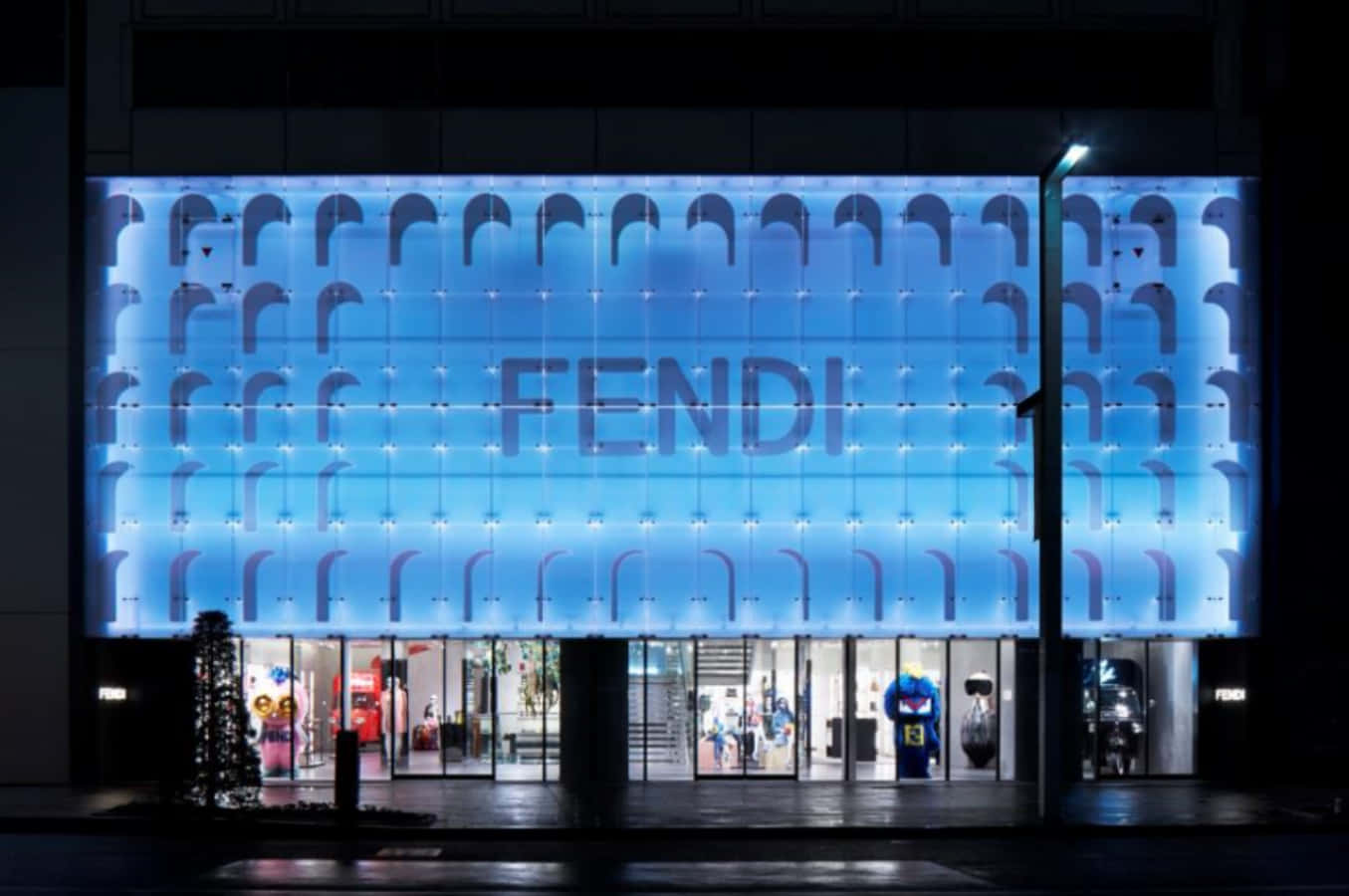Fendi 桌布 壁紙 — FENDI 商店外牆在夜間被發光的藍色燈光和重複的拱形圖案照亮。
