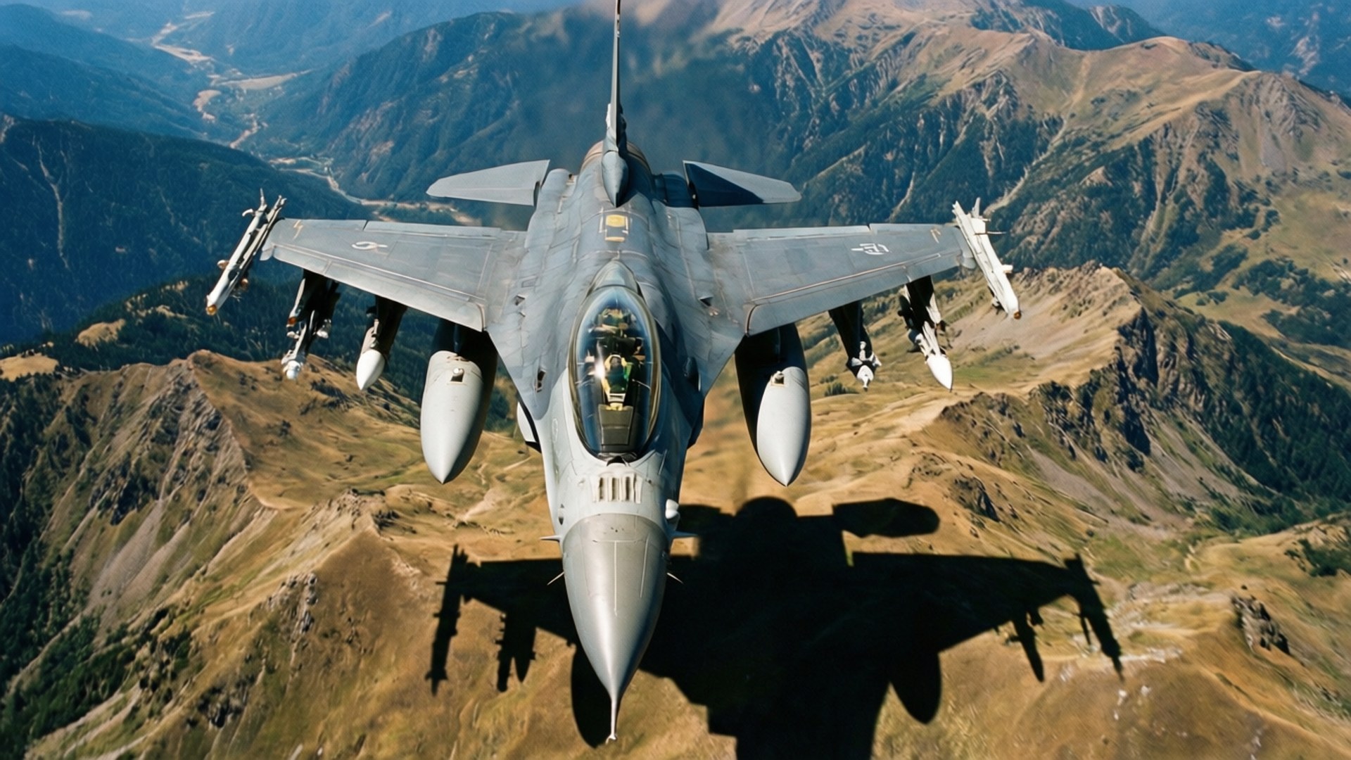 F-16 桌布 壁紙 — 一架戰鬥機在崎嶇的山地低空飛過，下方投下清晰的陰影。