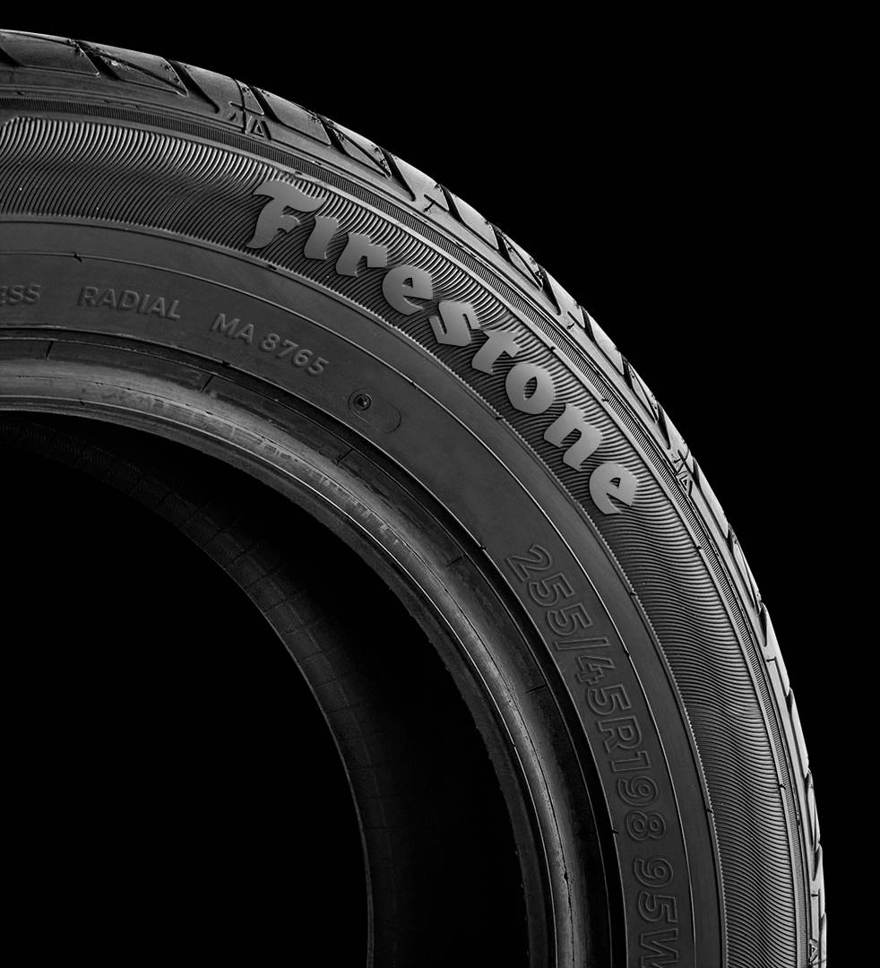 Firestone 桌布 壁紙 — Firestone 輪胎胎面特寫，以純黑背景凸顯其精細的溝槽和壓花文字。