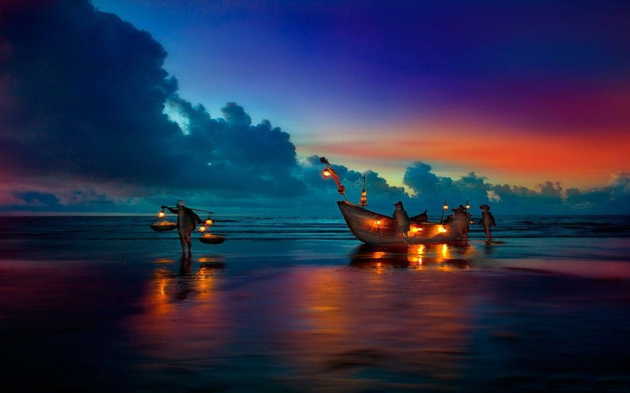 海灘 桌布 壁紙 — 漁民在黃昏時分提著發光的燈籠走過濕漉漉的海灘，他們的船反射出火熱的橙色和深藍色的天空色調。