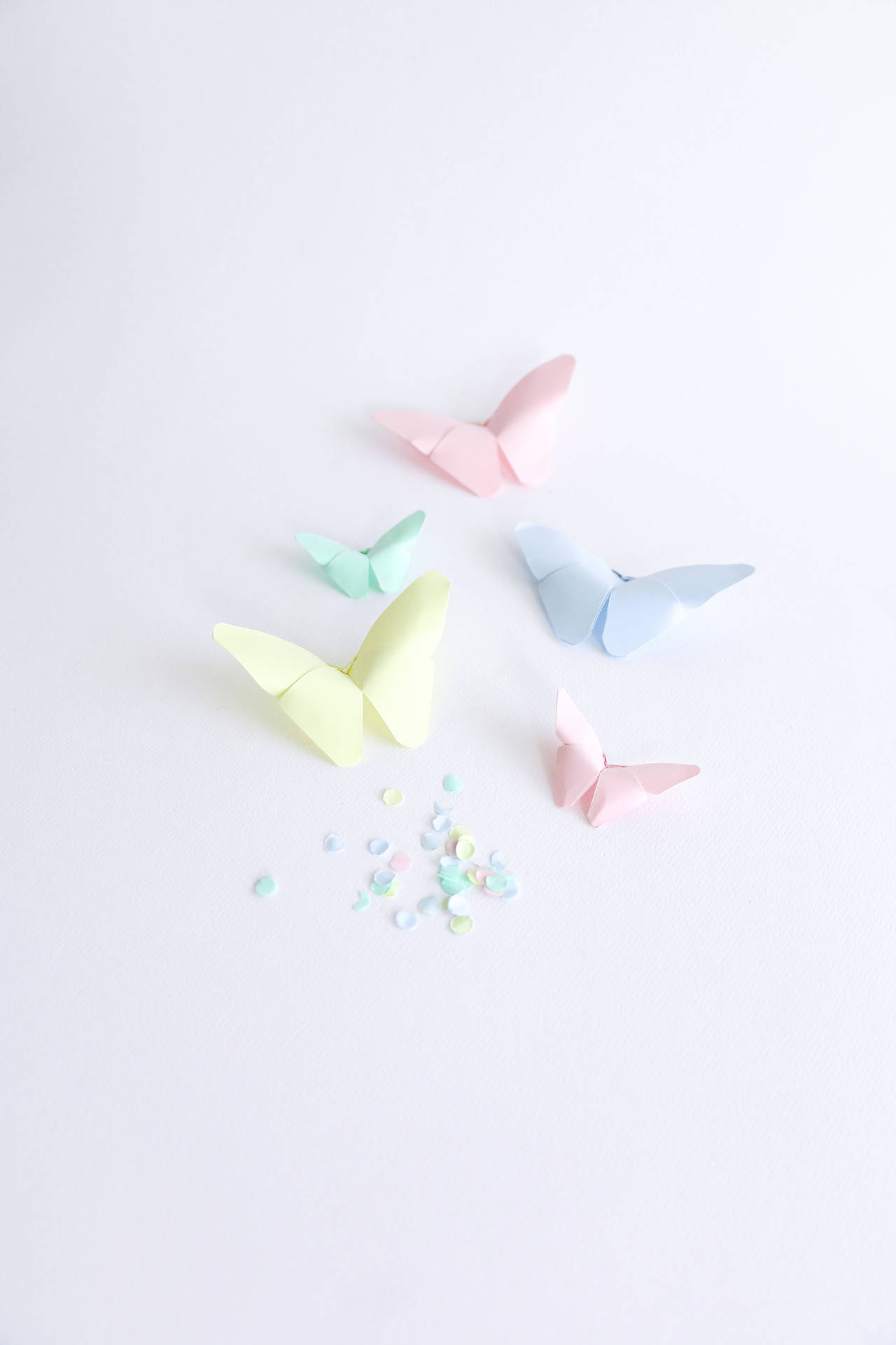 白色背景上的五隻粉彩紙蝴蝶和五彩紙屑。 — Pastel 壁紙