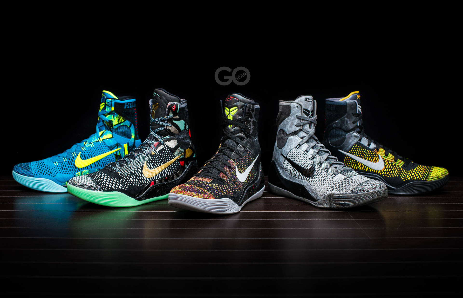 五雙色彩繽紛的Nike籃球鞋在深色木地板上排成一排。 — Jordan Logo 壁紙