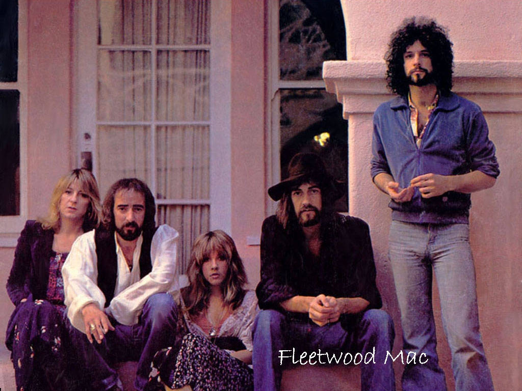 band 桌布 壁紙 — Fleetwood Mac 樂團成員穿著70年代風格服裝，在帶有白色飾邊的粉紅色灰泥建築前擺姿勢。