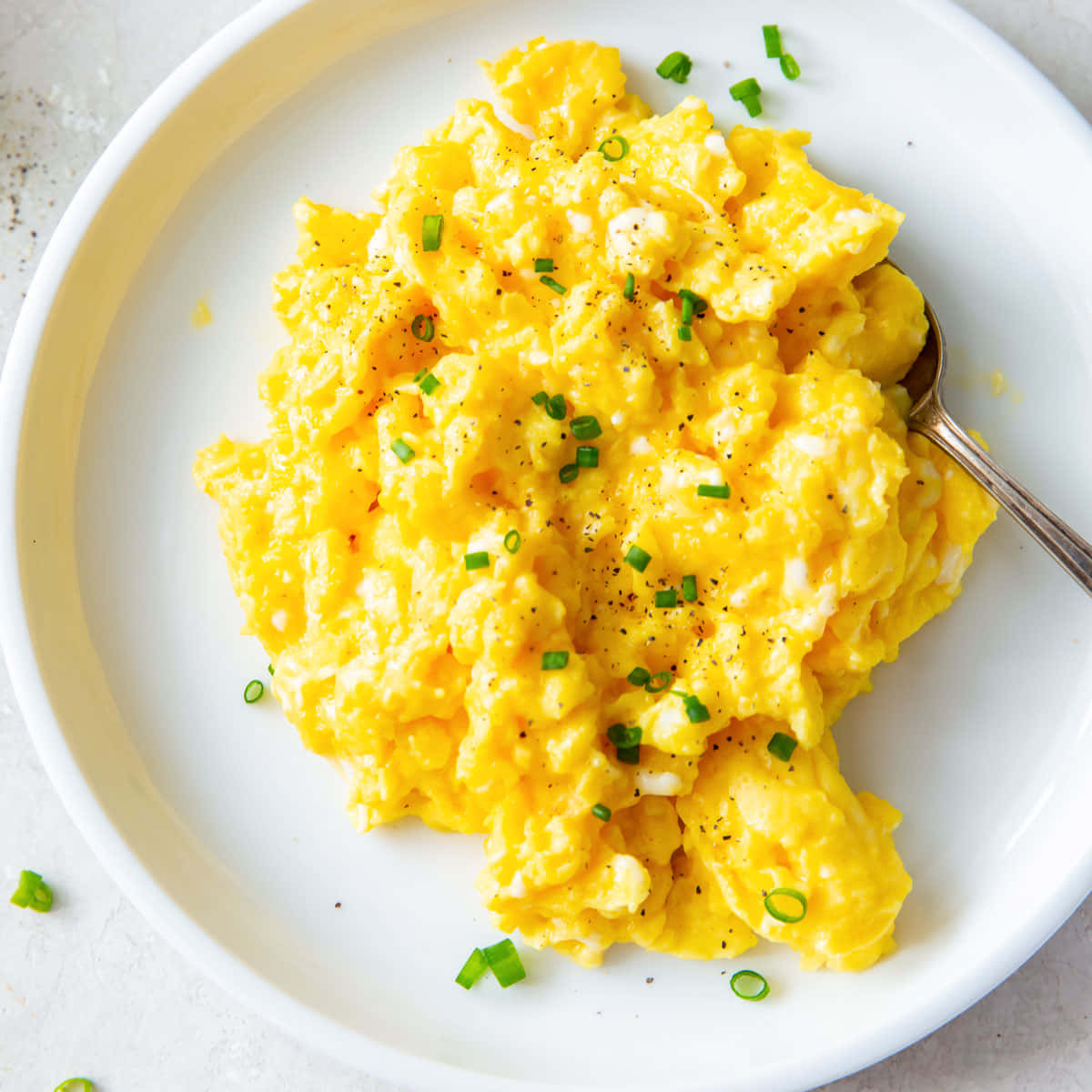 Scrambled Egg 桌布 壁紙 —  fluffy 黃色炒蛋，配上綠色細香蔥和黑胡椒，放在白色盤子上，附有湯匙。