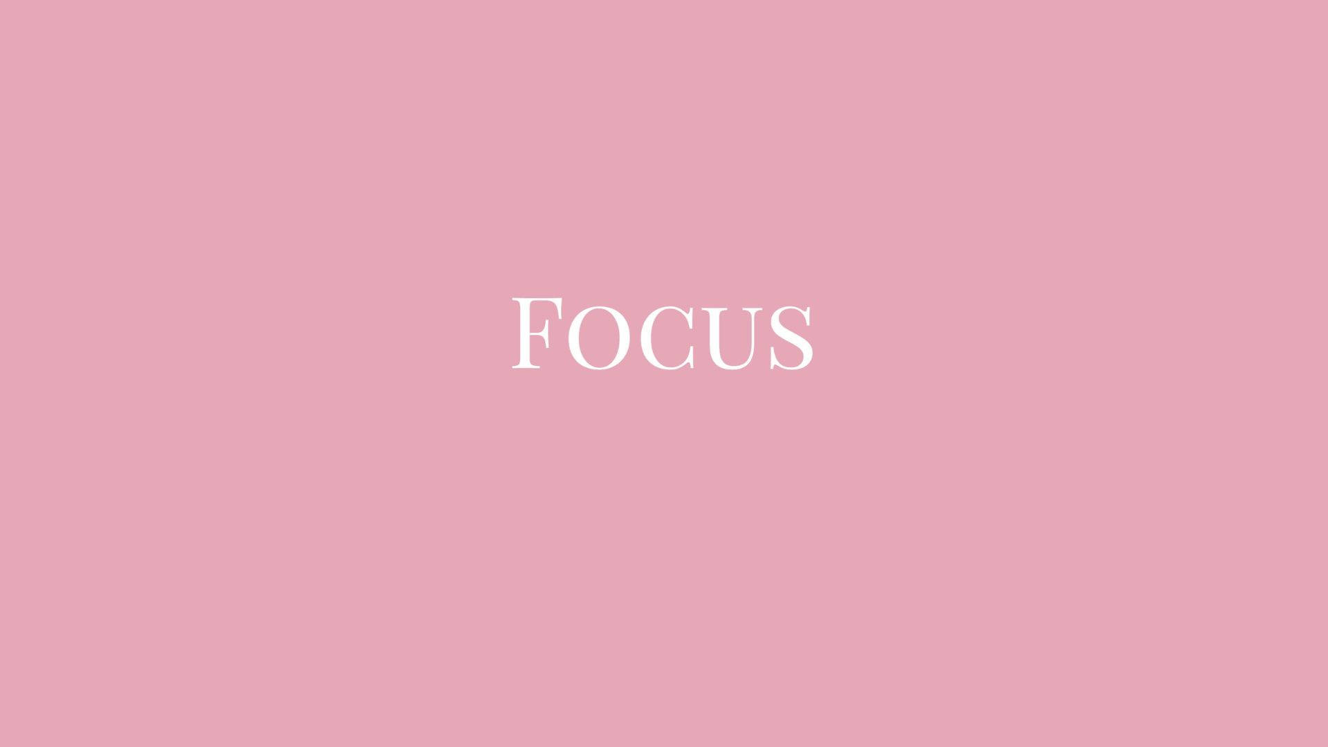 美學粉色GIF 桌布 壁紙 — 「focus」一詞以優雅的白色襯線字體居中顯示在純色柔和粉紅色背景上。
