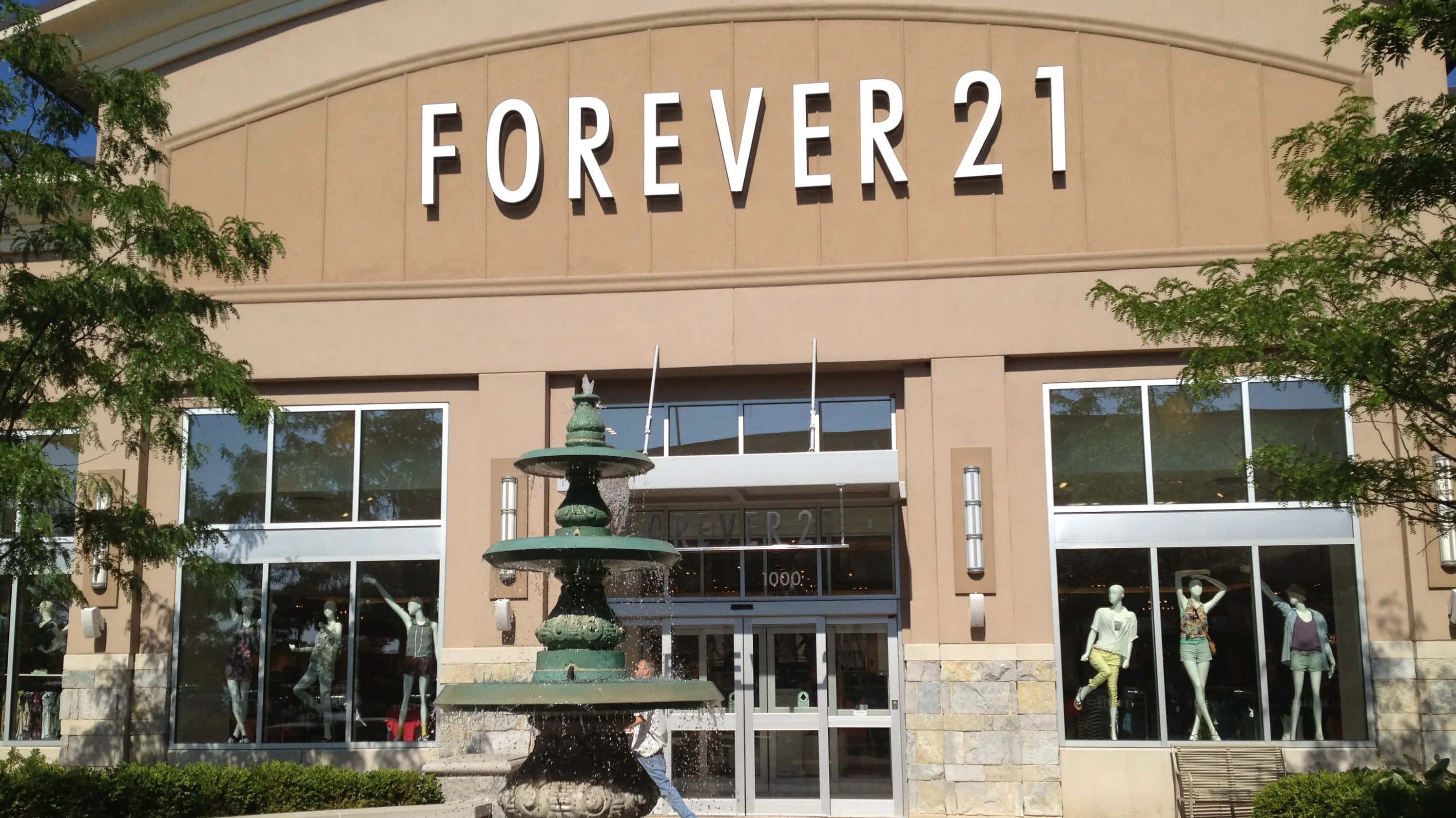 永遠21 桌布 壁紙 — Forever 21 店鋪外觀的晴朗日間照片，前面有綠色噴泉，櫥窗內有模特兒。