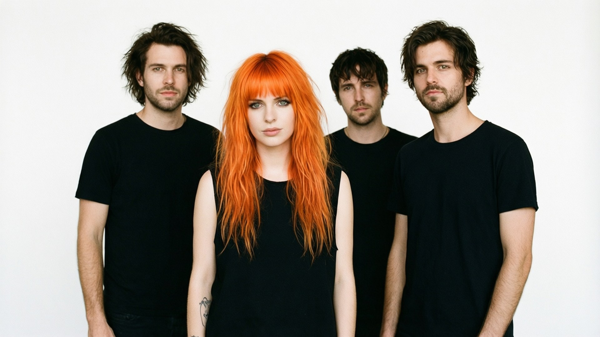 Minimalist Paramore 壁紙 — 四位樂團成員在純白背景前擺姿勢，其中一位女士擁有鮮豔的橙色頭髮，其他人穿著黑色T恤。