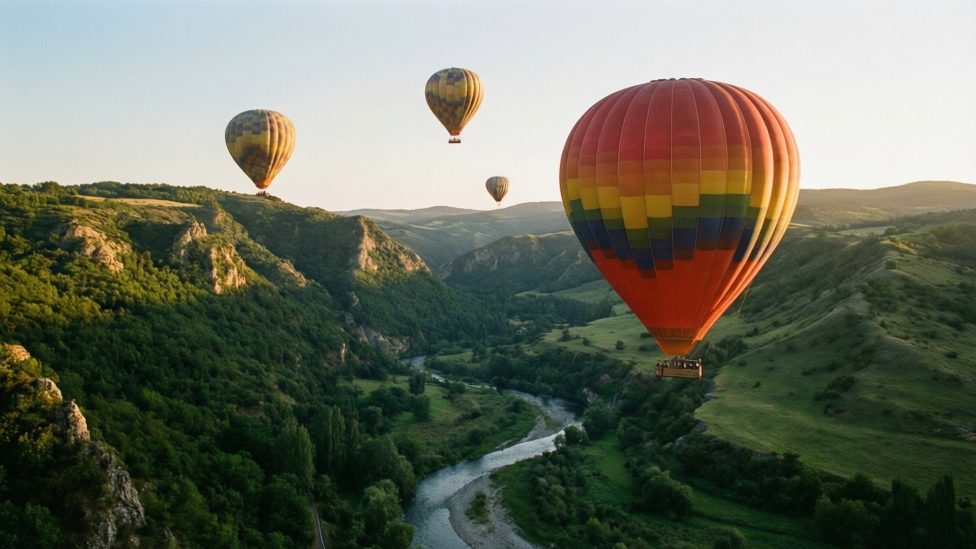 Balloon Valley 壁紙 — 四個色彩繽紛的熱氣球在日出時分飄過蜿蜒的河流，穿過鬱鬱蔥蔥的山谷。